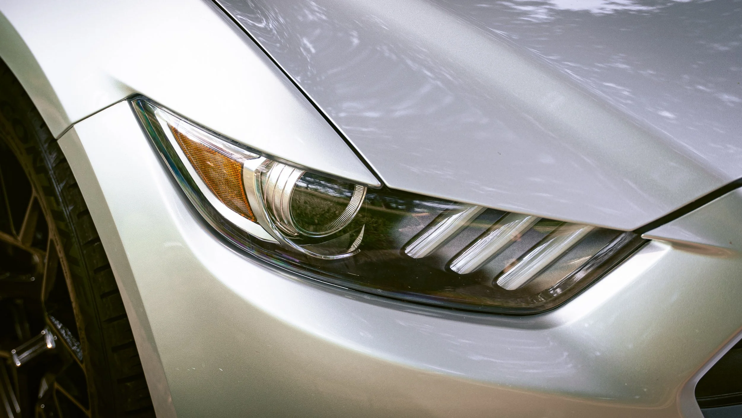 Close-up of a car front end showing the headlight, grille, and part of the white body.