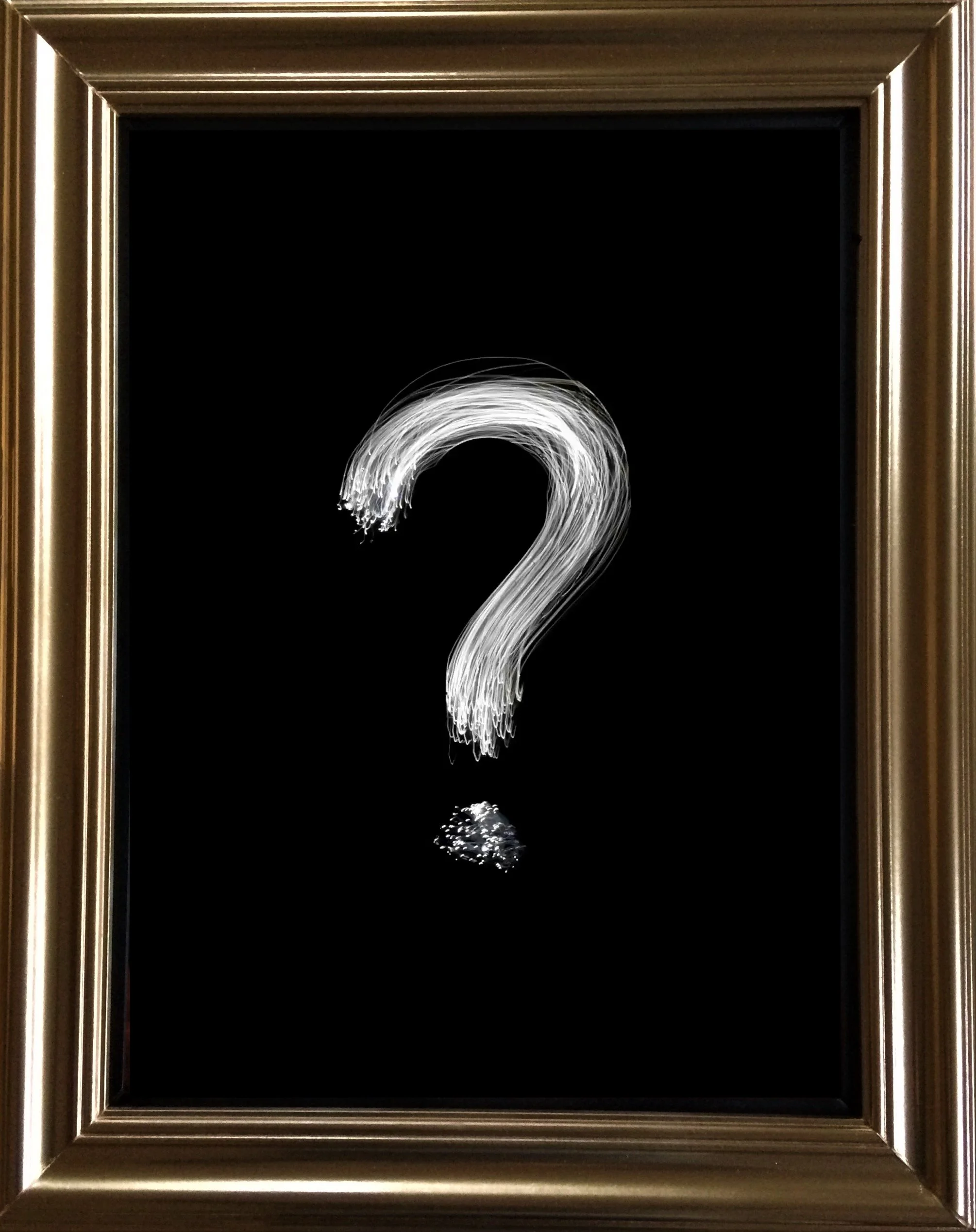 A black framed piece of art with a white zigzagging line and a question mark in the center