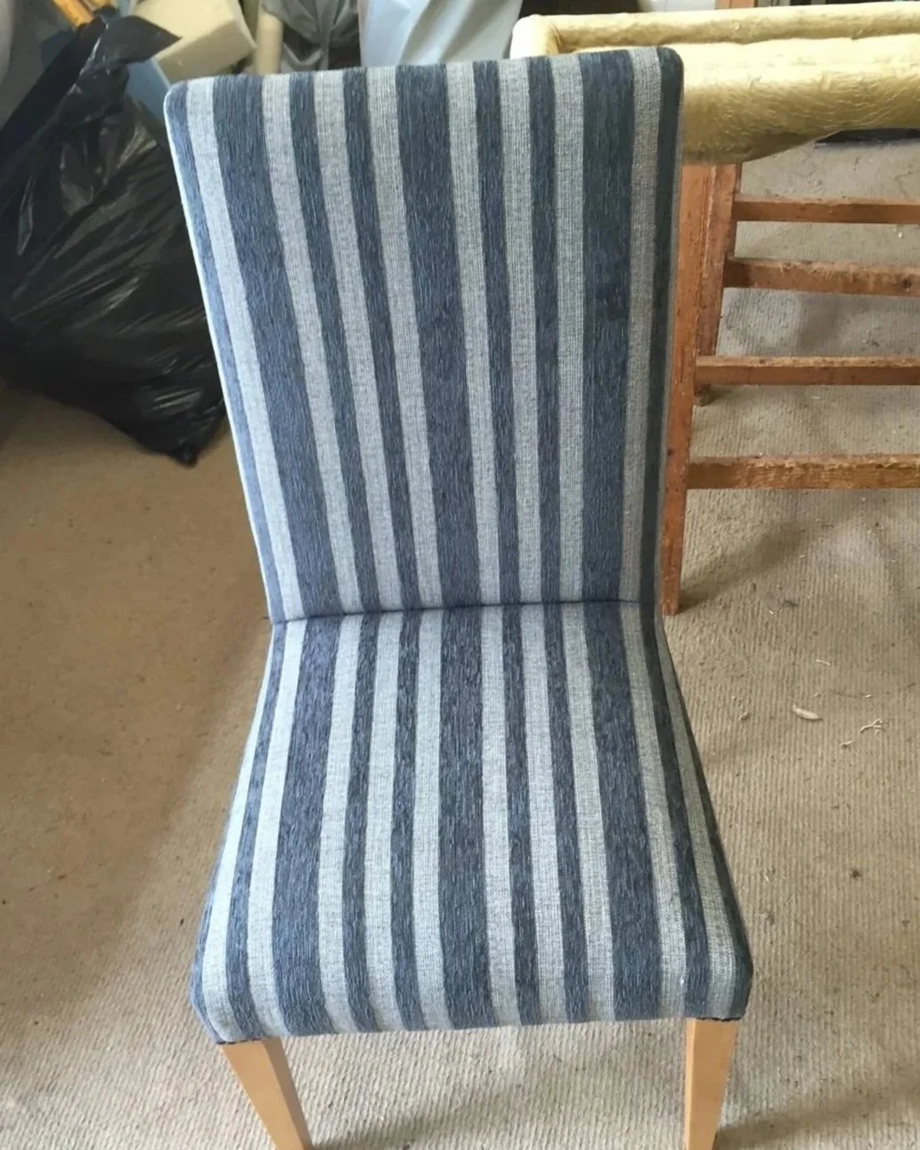 A dining chair with a wooden frame and a fabric cushion seat and backrest. The fabric has a striped pattern in shades of blue and gray.