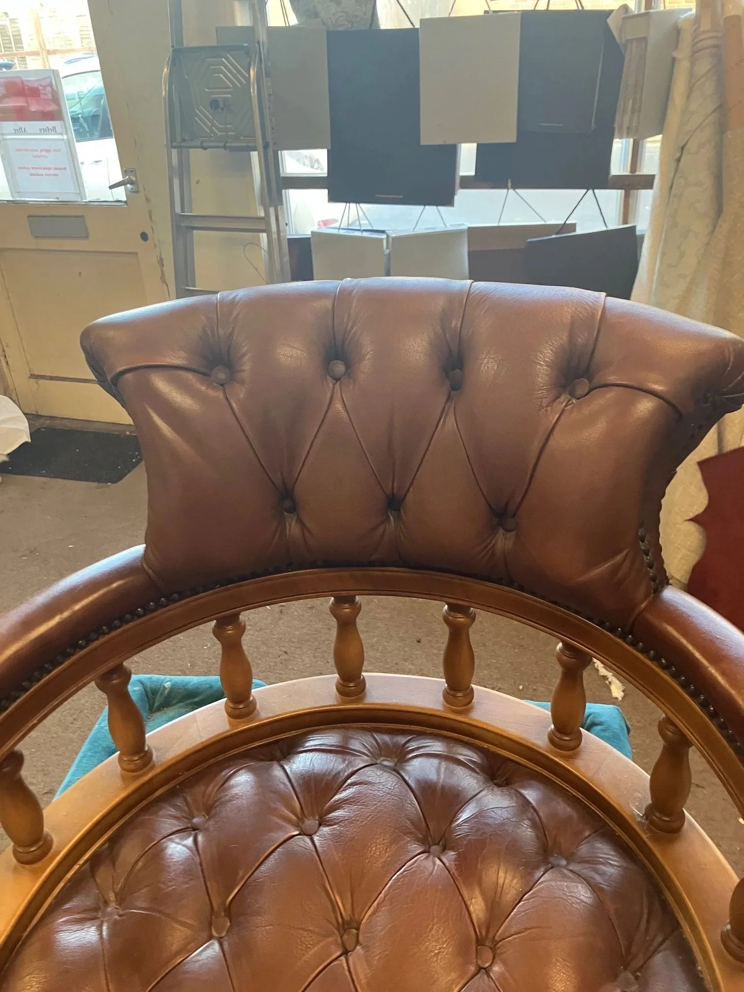 Wooden chairs with leather cushions in a store with a door and window in the background.