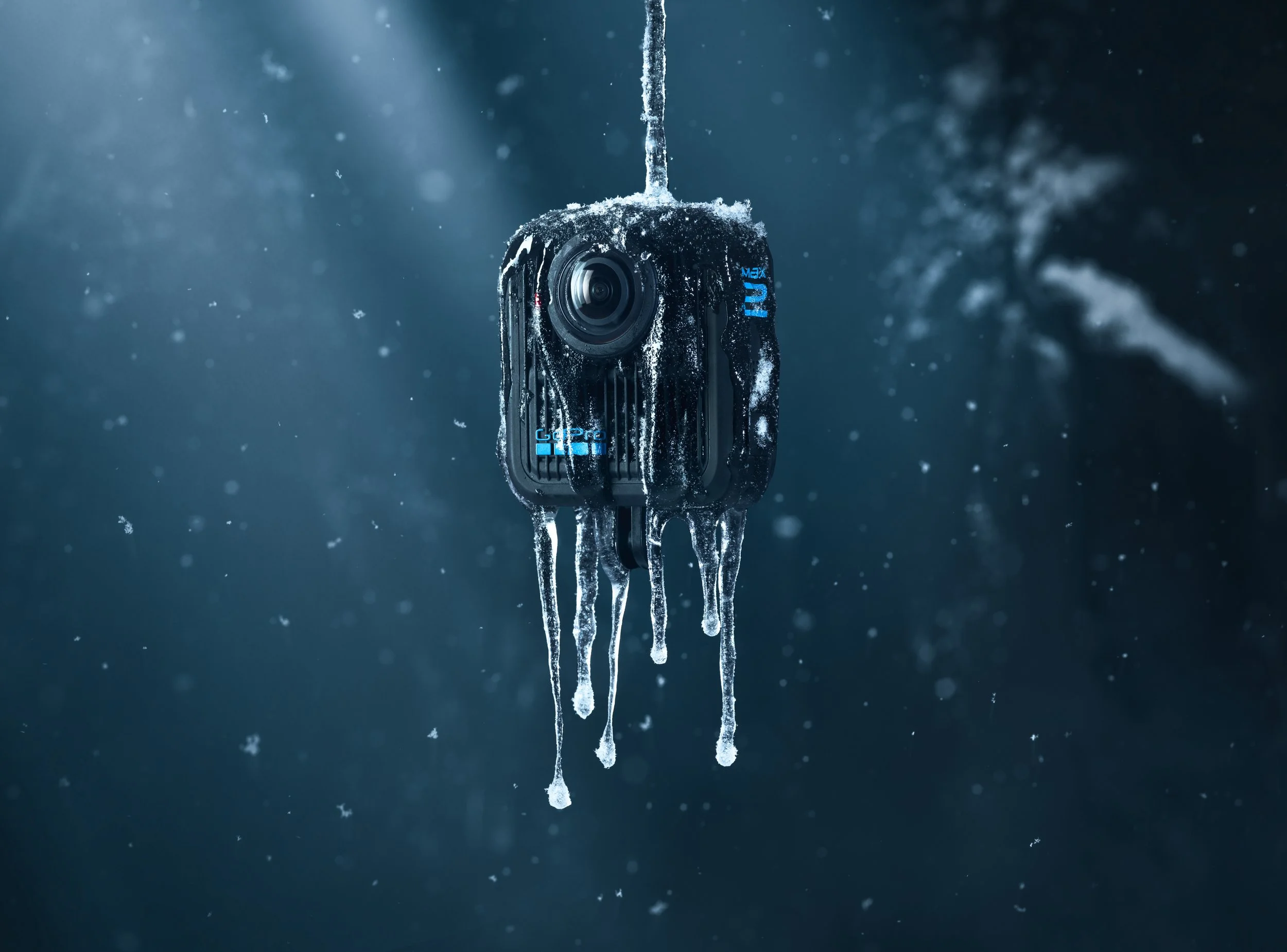 A black action camera covered in snow and ice, hanging from a string against a dark, snowy background.