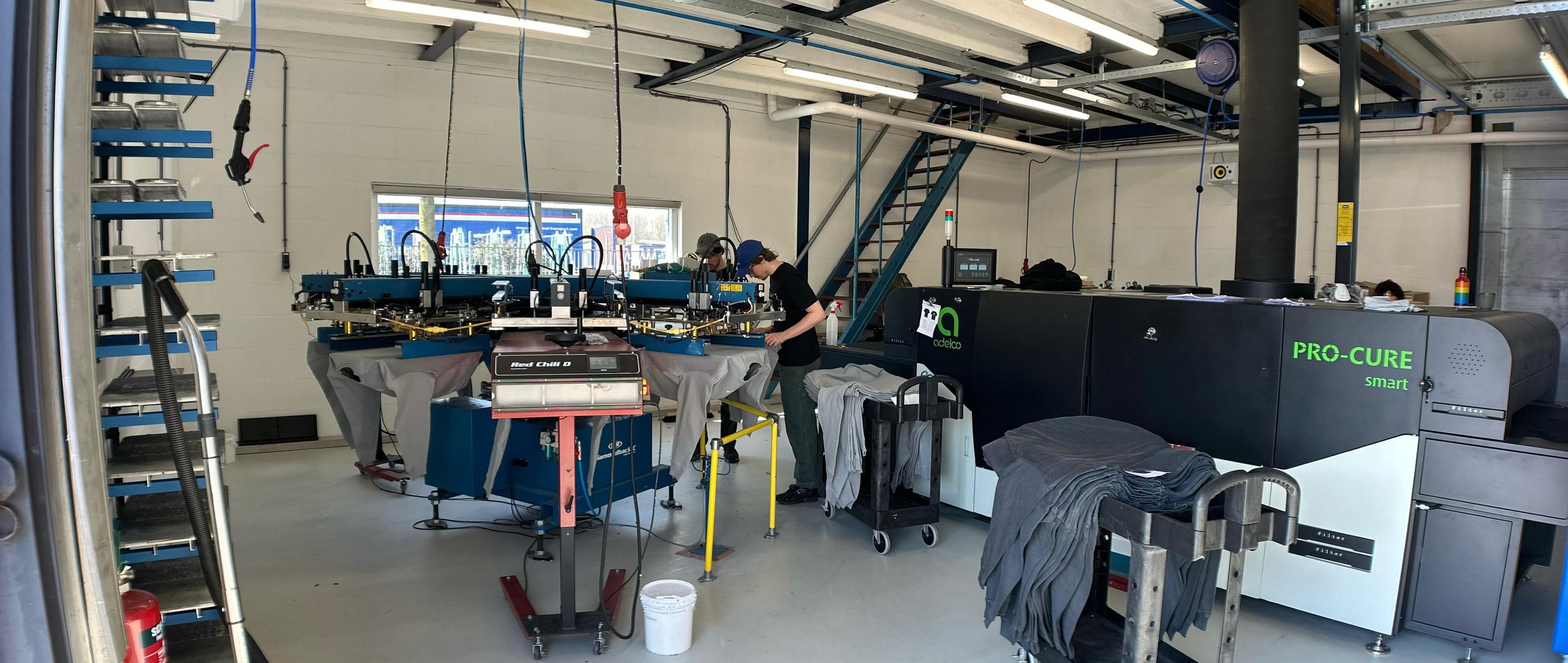 Overzicht van onze professionele werkplaats in Utrecht, uitgerust met industriële zeefdrukmachines voor kwalitatieve textielproductie.