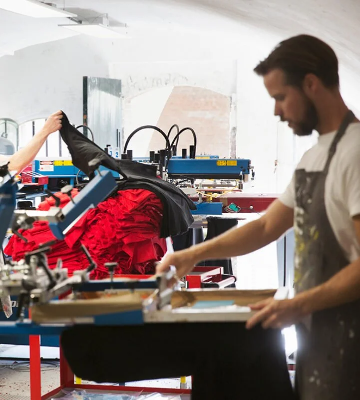 Een medewerker gebruikt milieuvriendelijke inkten voor textielbedrukking in onze professionele werkplaats.