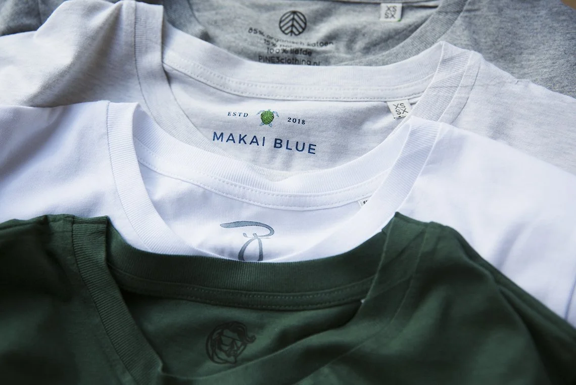 Gedetailleerde opname van custom nek-labels en merklogo's in kleding; wij verzorgen professionele kledingafwerking met labels, hangtags en verpakking voor jouw eigen kledinglijn in Utrecht.