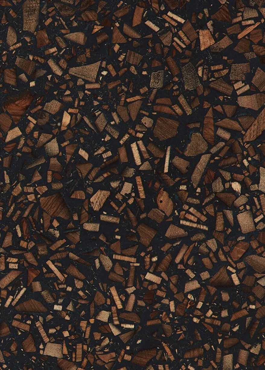 Close-up of a terrazzo surface with small, irregularly shaped pieces of brown and tan stones embedded in a black background.