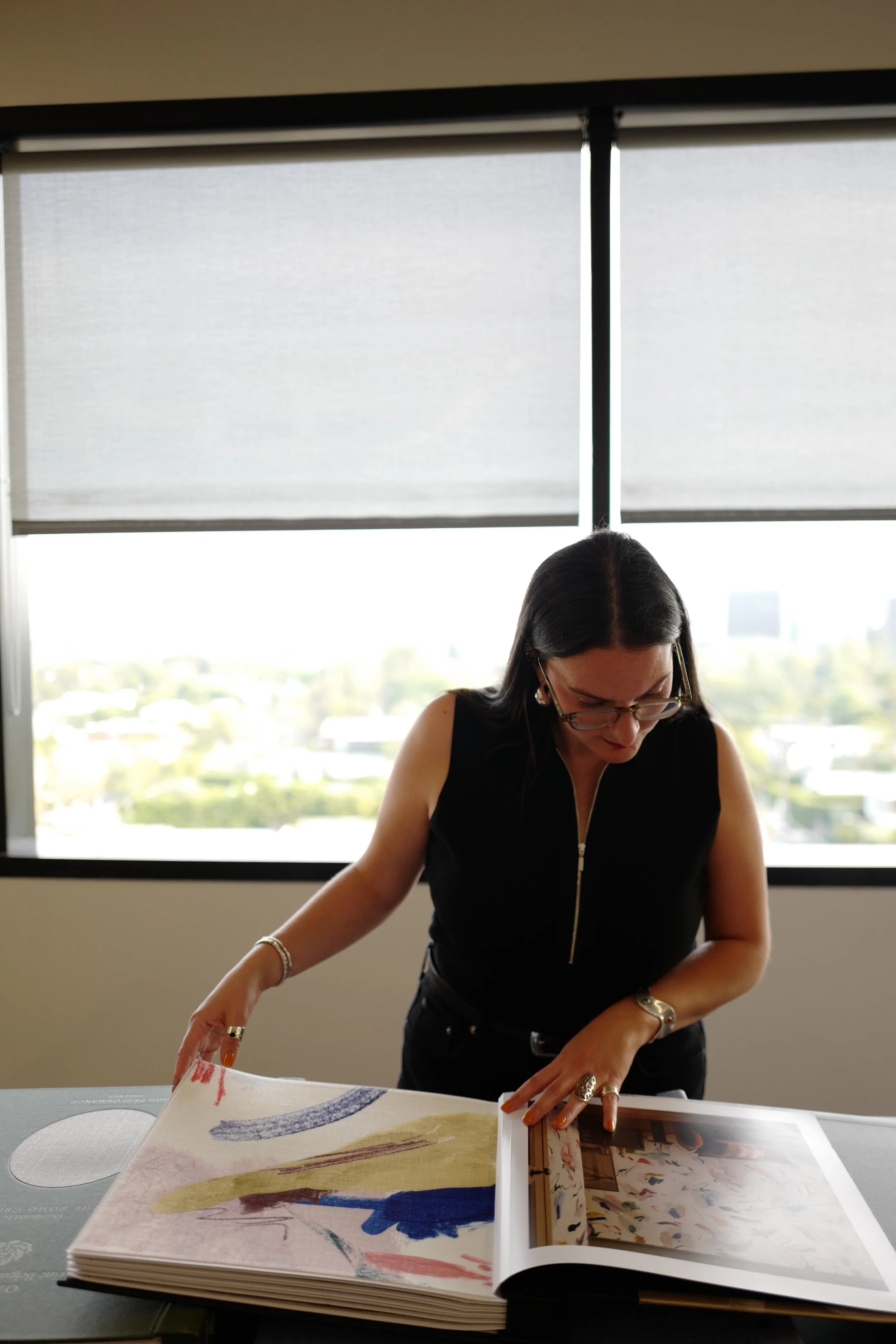 Interior designer reviewing art books and design references during project research phase