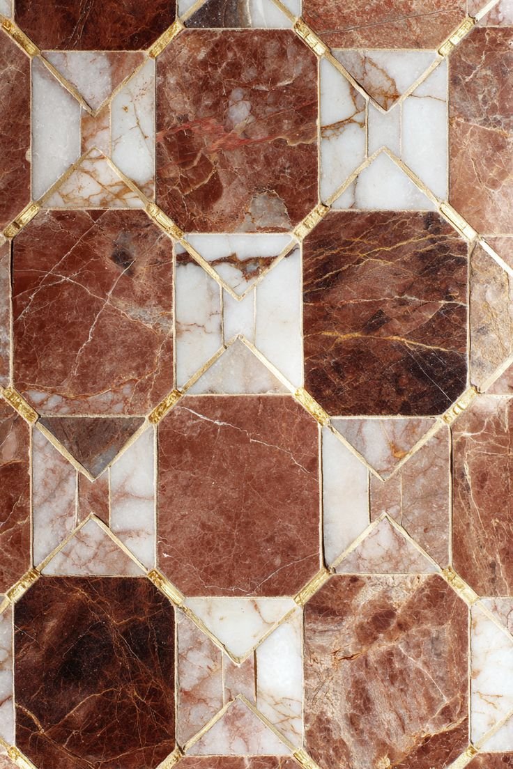 Close-up of a decorative tile pattern with red, white, and pink marble tiles bordered by gold accents.