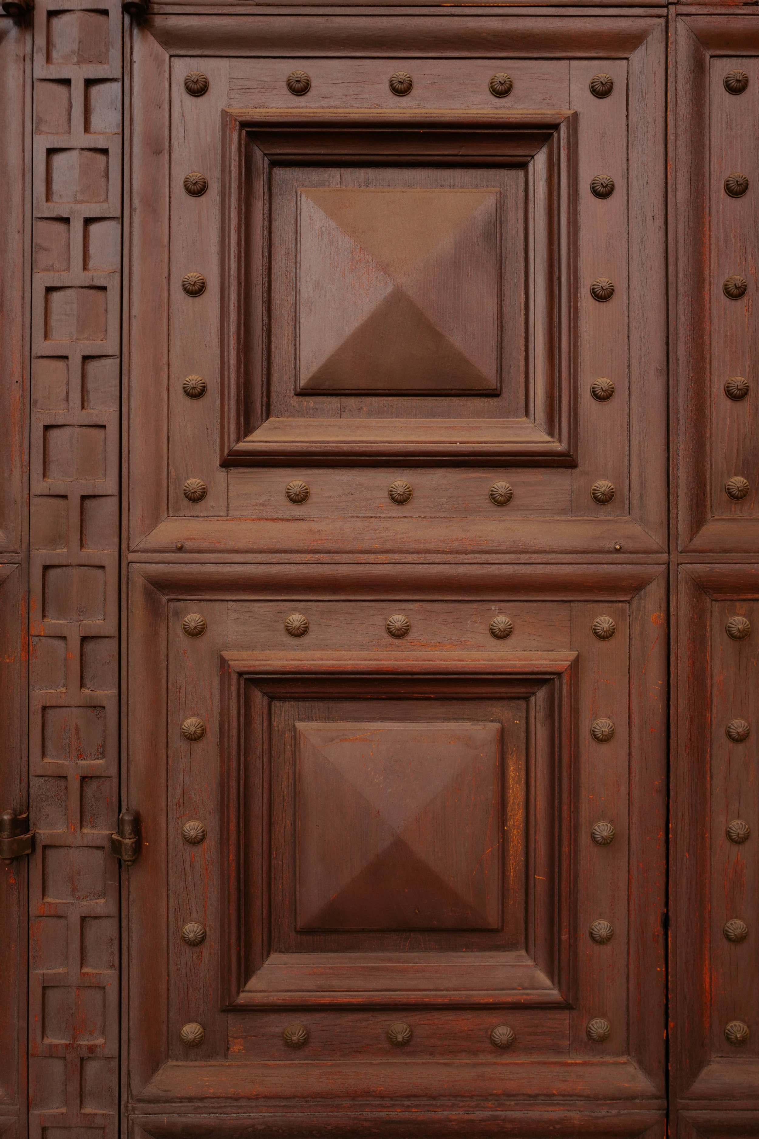 Ornate carved wood door with studded detail on a Spanish Revival historic home