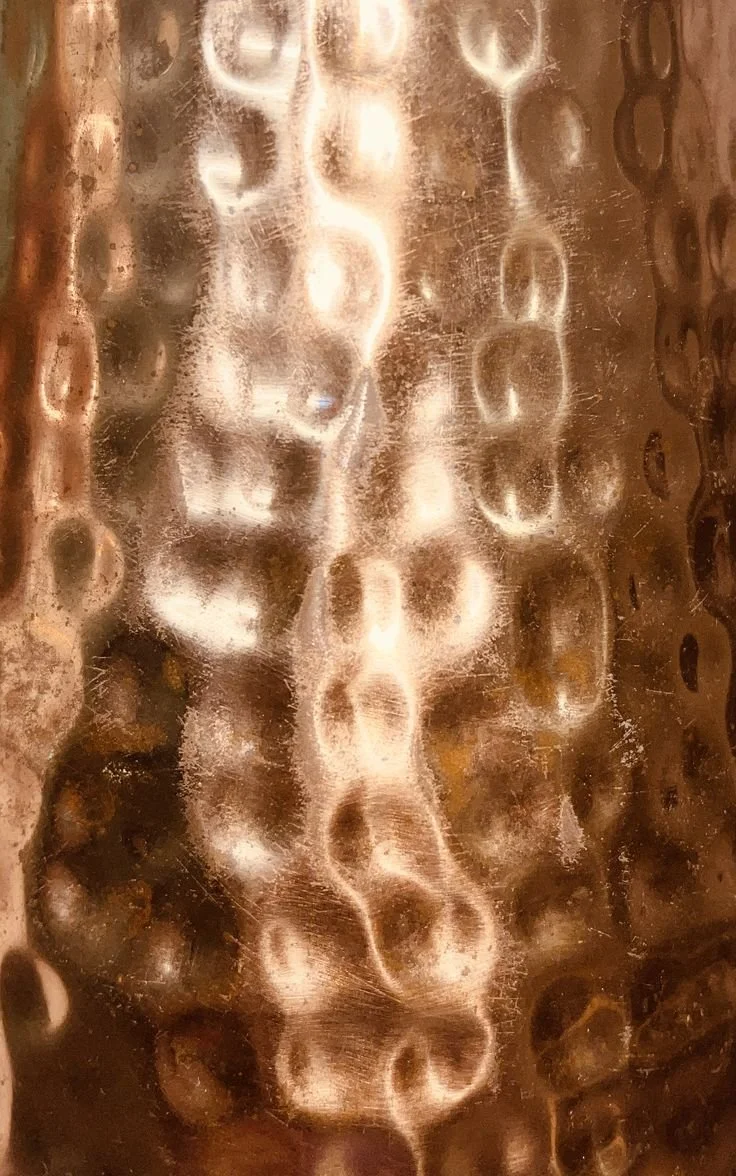Close-up of a metallic surface with a pattern of circular indentations reflecting light.