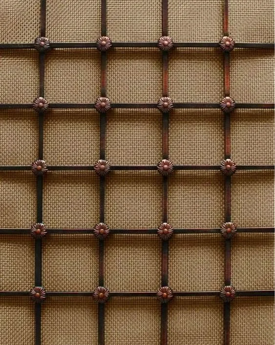Close-up of a woven rattan or wicker surface with a grid of dark brown wooden slats and decorative metal caps at each intersection.