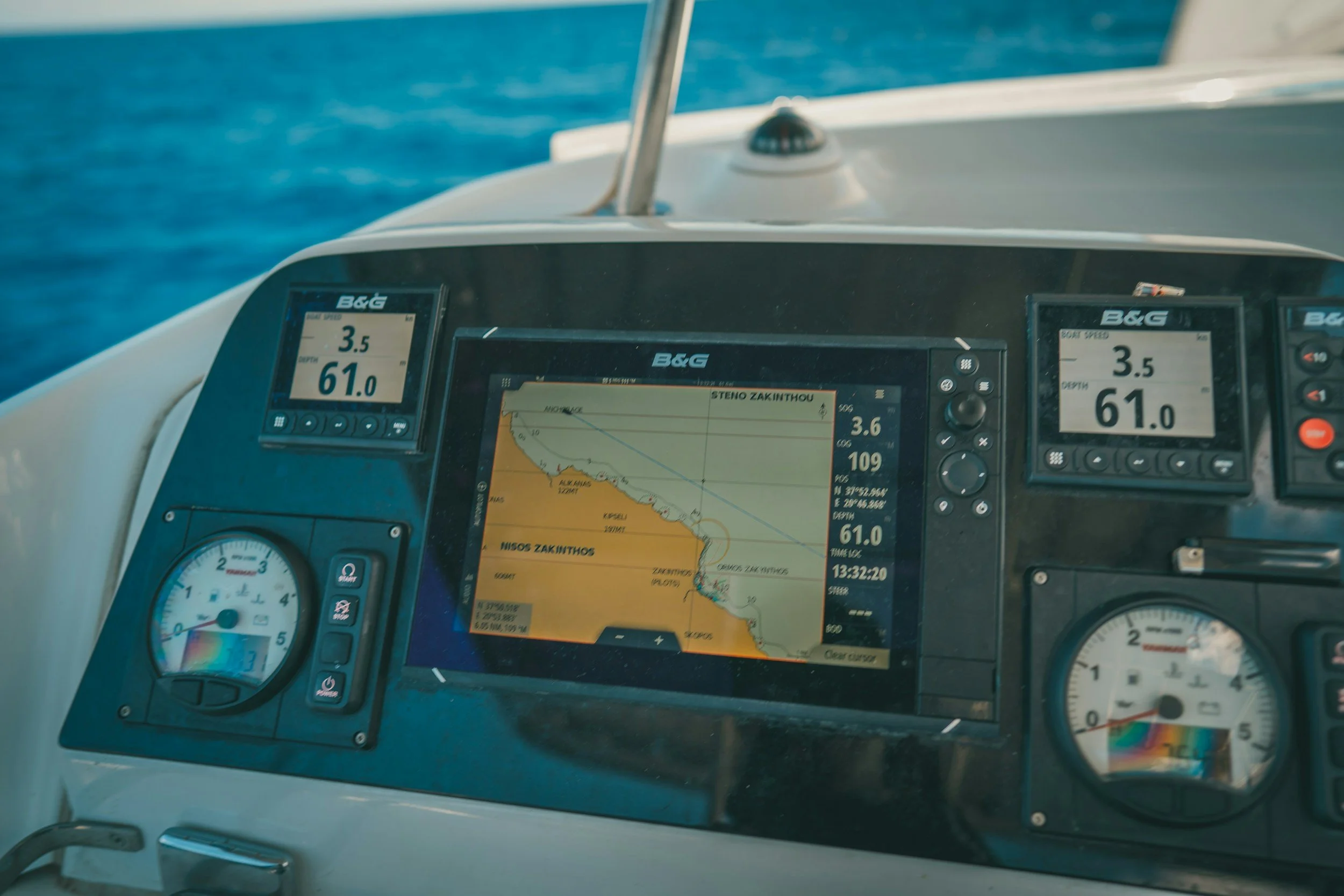 Close-up view of navigation and instrument displays at a catamaran sailboat helm station with a gps chartplotter, depth, and speed readings