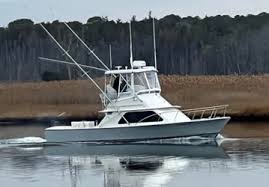 A white fishing boat on calm water with trees in the background.
