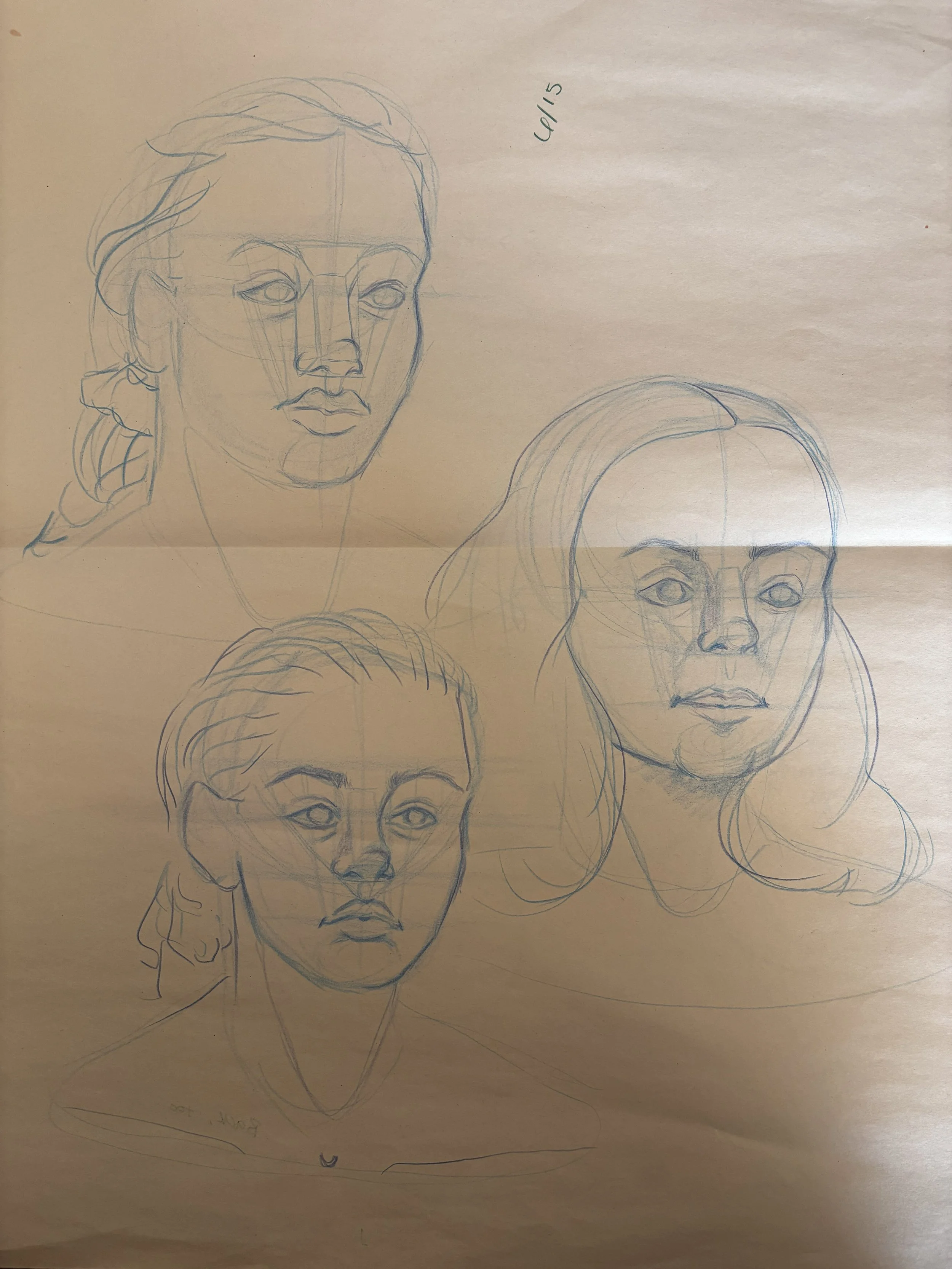 Sketches of three female faces in pencil on paper, with some guidelines visible.