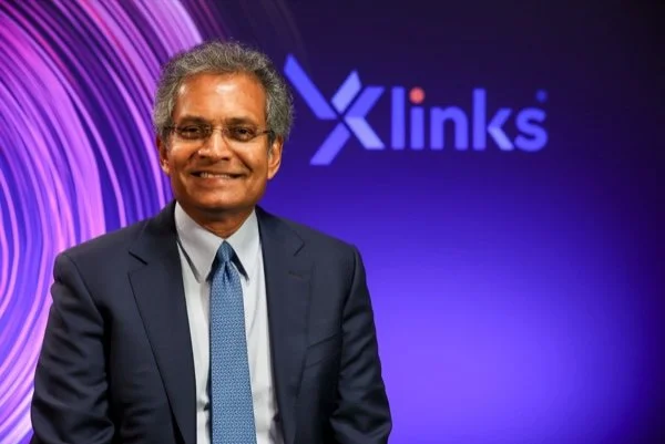 Paddy Padmanathan, former CEO of Acwa Power and advisor to NatureProsperity. A smiling man in a suit and tie standing in front of a purple background with the 'X links' logo.
