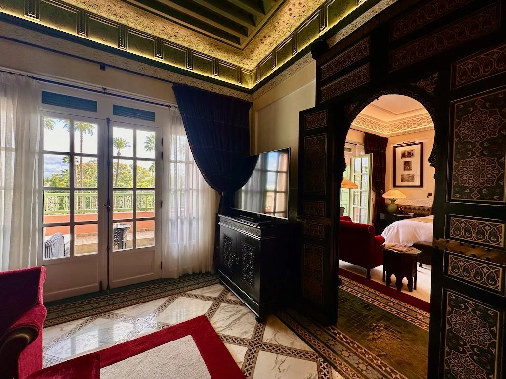 Guest room at La Mamounia in Marrakech with carved Moroccan woodwork, a double balcony, and views over the historic gardens.