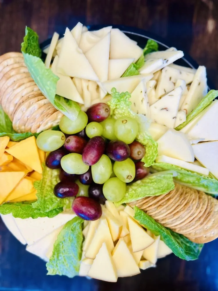 Cheese platter with grapes, lettuce, and crackers