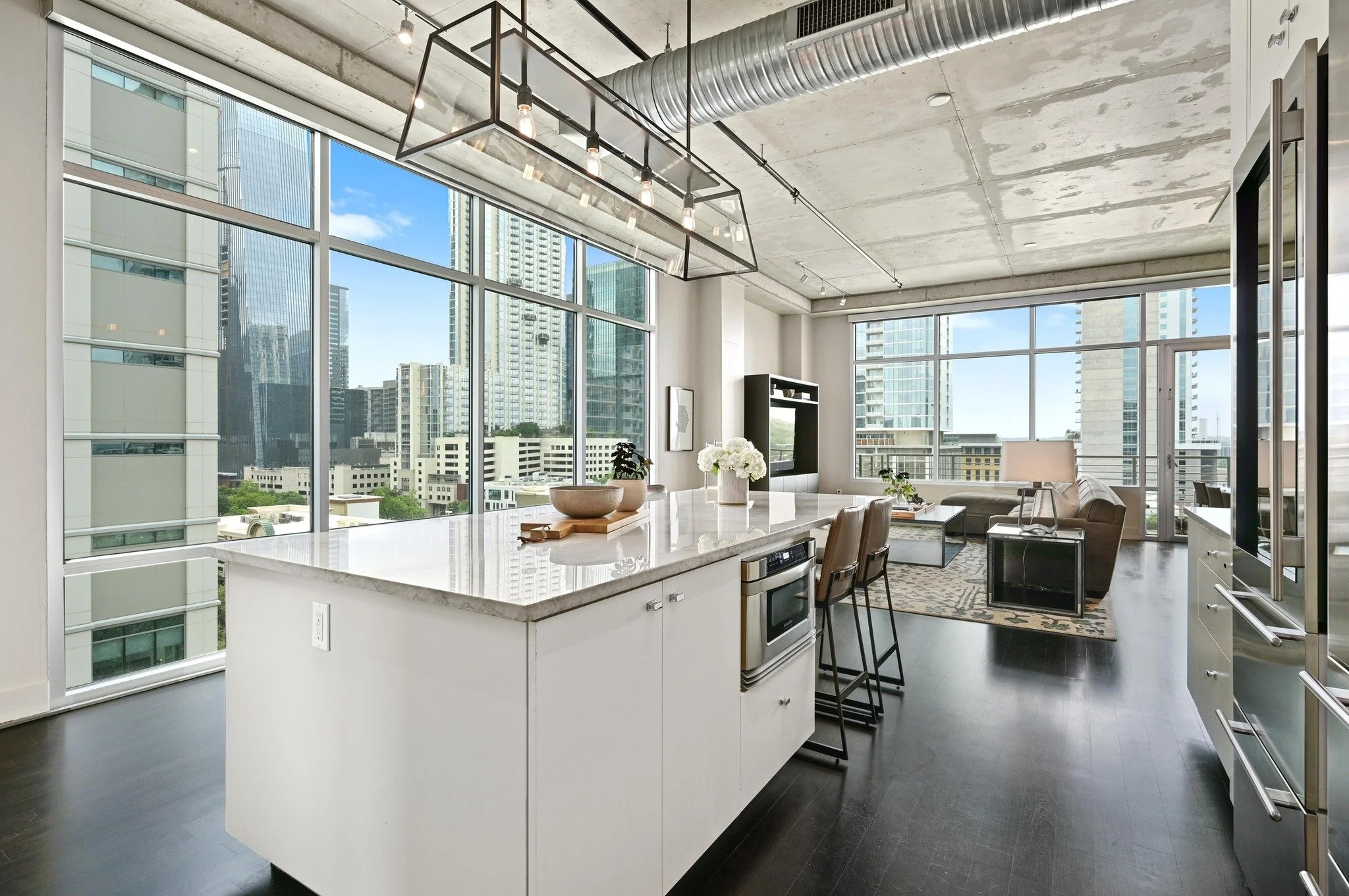 Sleek, sophisticated kitchen at 800 W 5th Street #808 in Downtown Austin, featuring top-tier appliances, clean-lined cabinetry, and an open connection to the expansive living and dining areas framed by floor-to-ceiling windows and panoramic city skyl