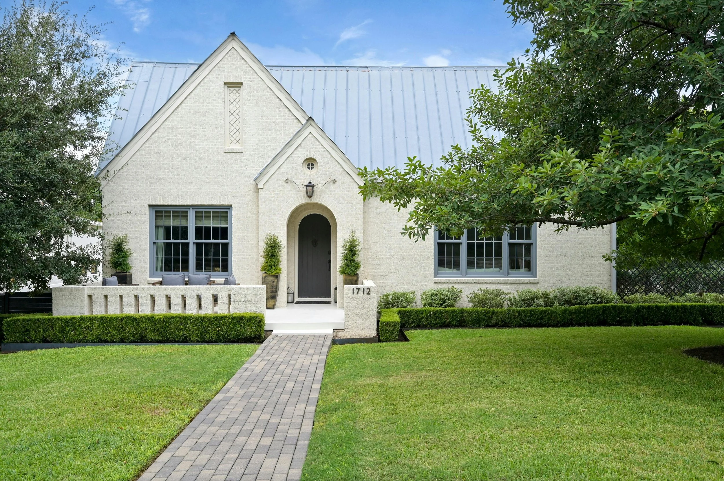 1712 Hartford: Charming exterior of a beautifully restored 1950s Tudor in Austin's prestigious Old Enfield neighborhood, showcasing timeless architectural character, lush mature landscaping, and the understated elegance of one of the city's most cove