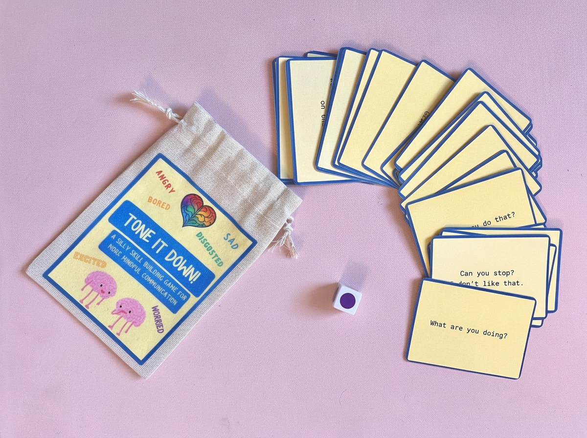 A card game called 'Tone It Down' with illustrated cards, a dice with purple dots, and a drawstring bag on a pink background.