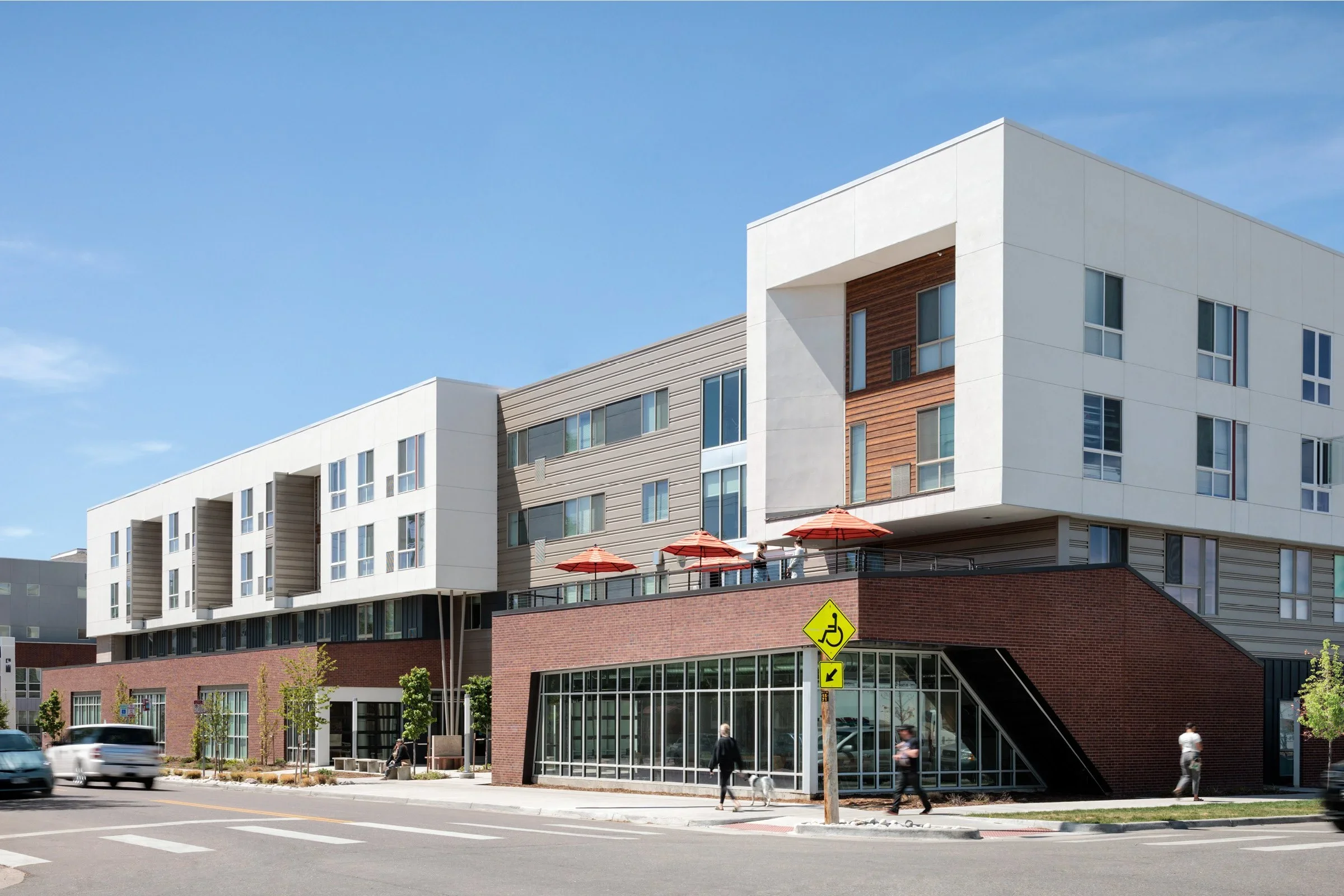 Atlantis Apartments, a four-story building with a brick ground floor and a shaded upper terrace