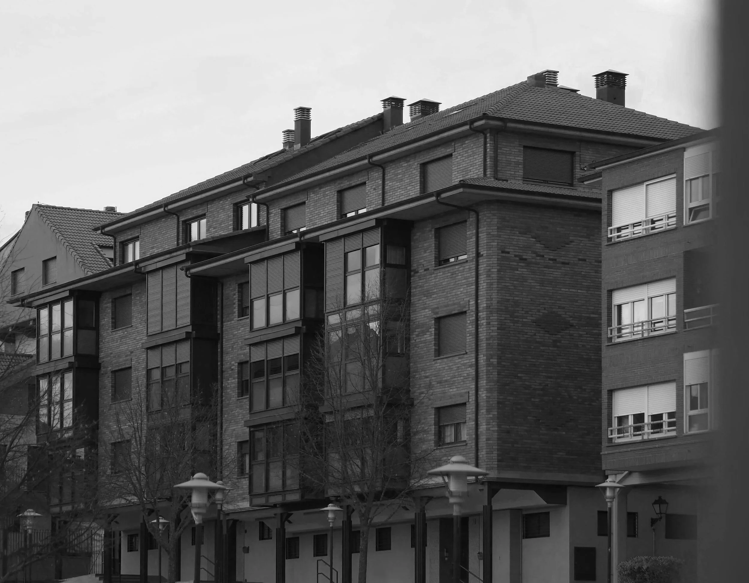 Edificio de apartamentos de varios pisos con ventanas y balcones de ladrillo, bajo un cielo despejado.