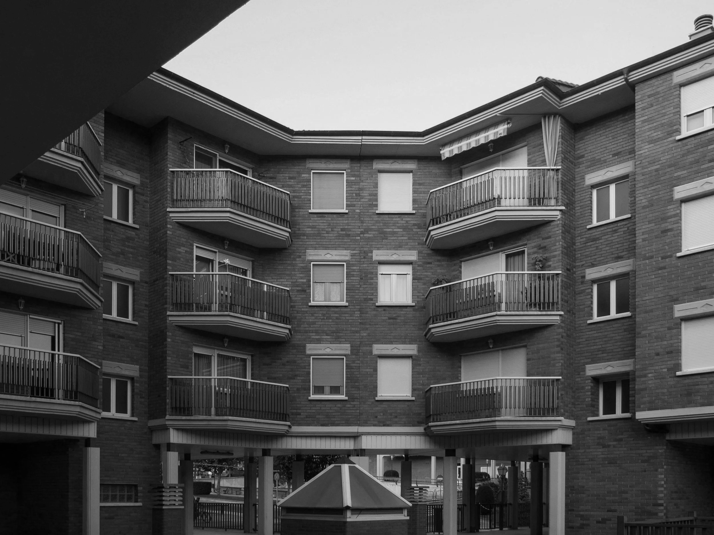 Edificio de apartamentos de varios pisos con balcones en el exterior, en una imagen en blanco y negro.