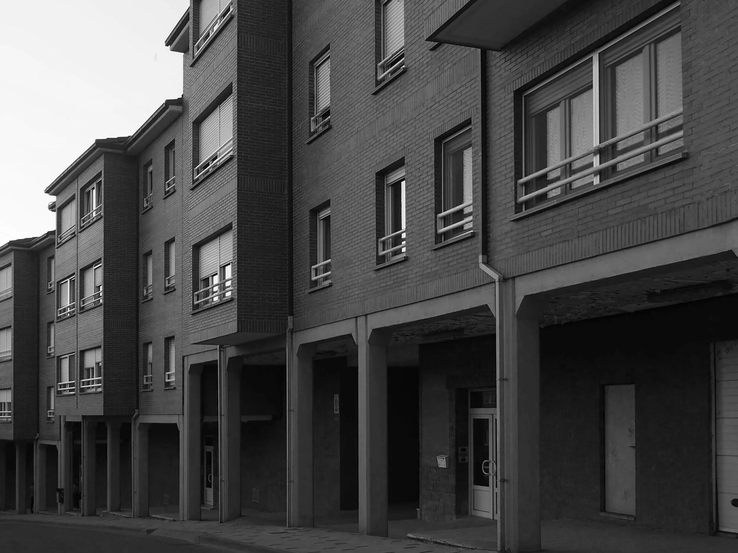 Edificio residencial de varios pisos con ventanas y balcones, estructura de concreto y ladrillo, en un entorno urbano.