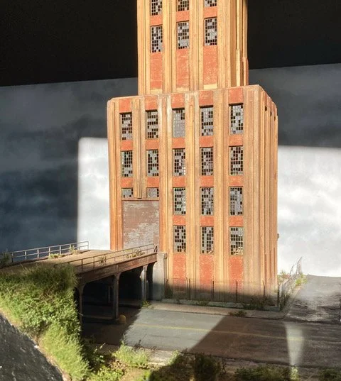 Model of a building with a clock tower, featuring an industrial design with brick and metal elements.