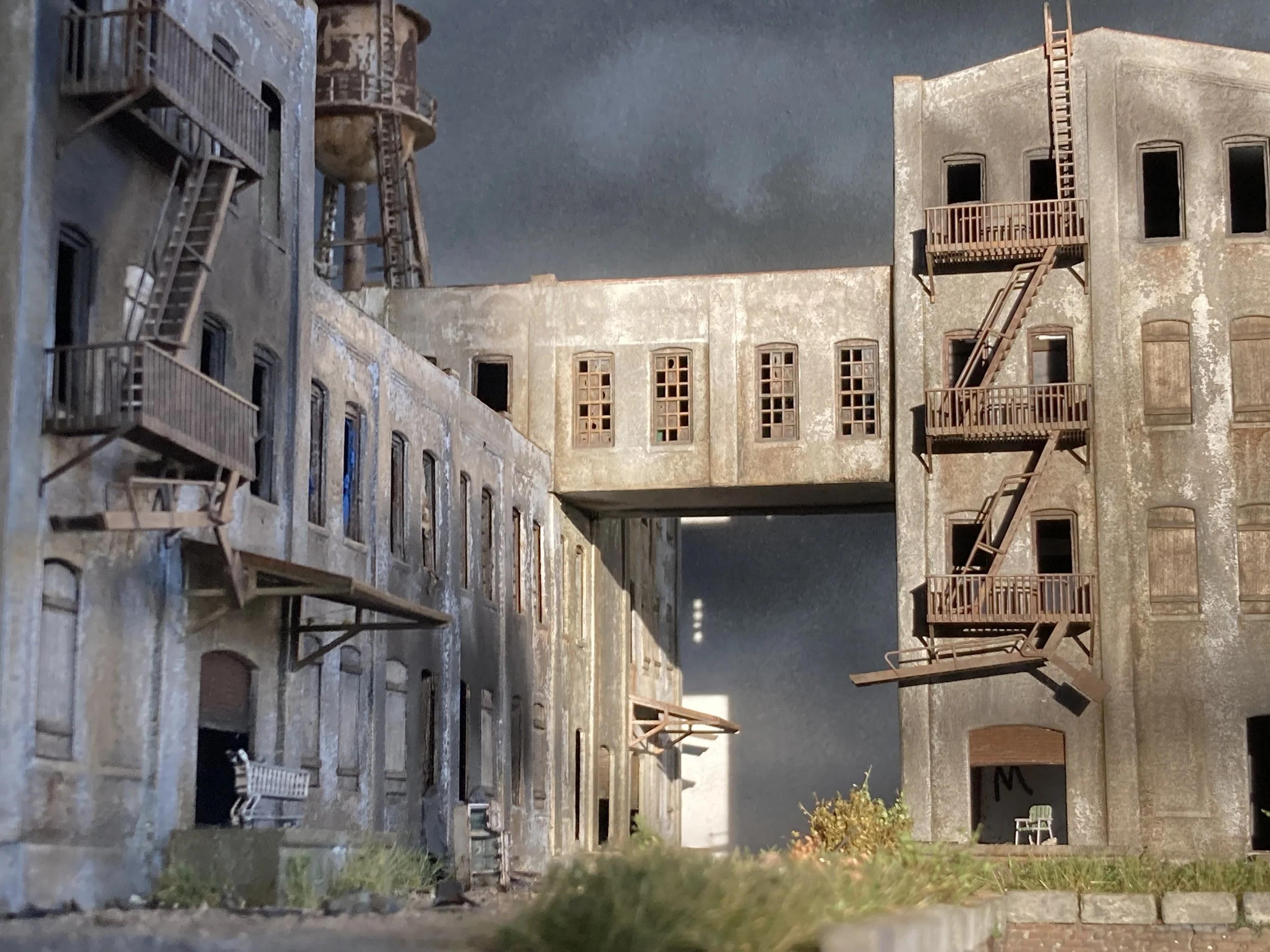 The image depicts a weathered, multi-story building with fire escape ladders attached to its exterior walls. The building's facade shows signs of age and peeling paint, and several windows are visible, some with broken or missing glass. There is a cl