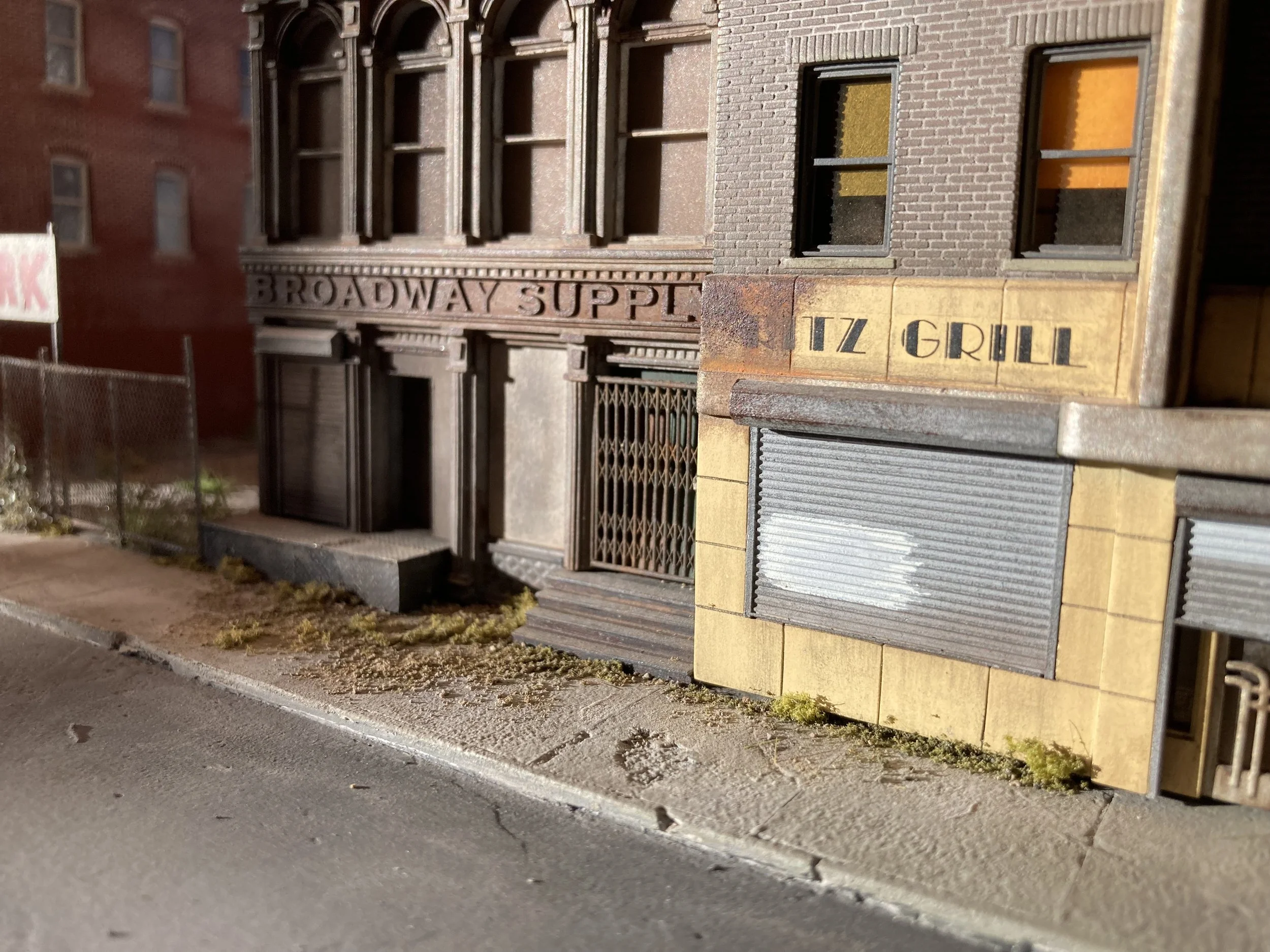 Miniature model of a building with signs that read 'Broadway Supply' and 'LZ Grill' located along a sidewalk.