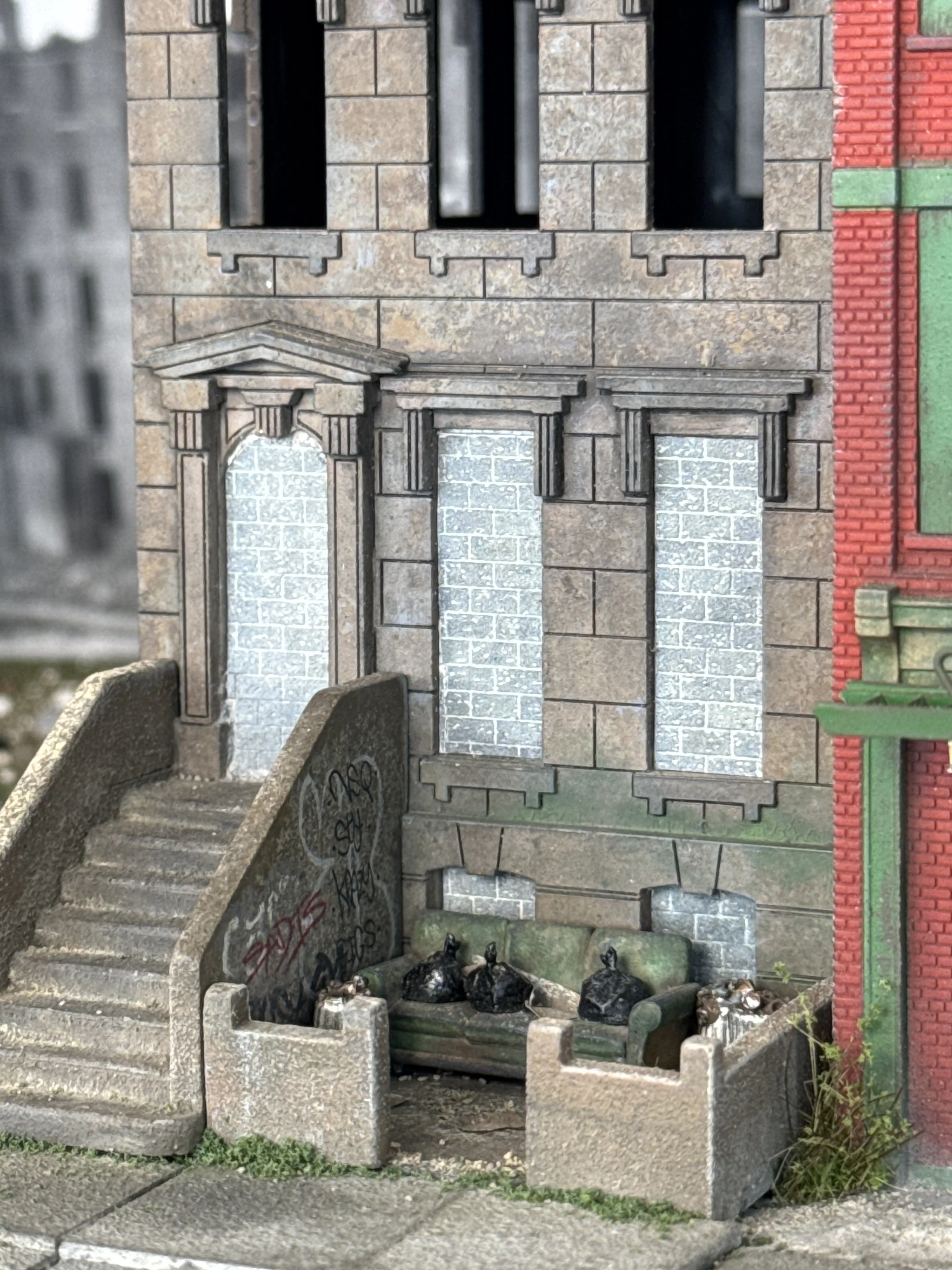 A miniature model of a building facade with a staircase and arched windows, decorated with graffiti at the base.