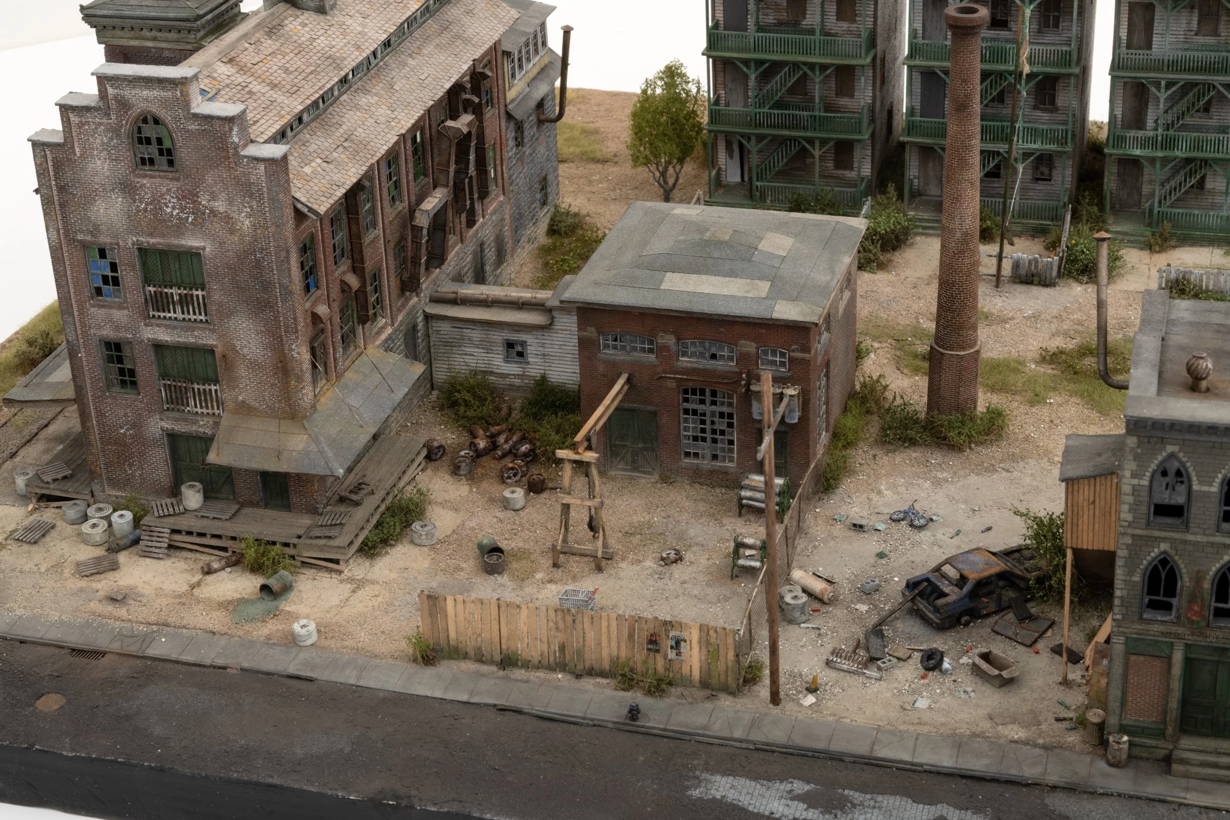 Model cityscape of an abandoned urban area with dilapidated buildings, debris, and overgrown vegetation.