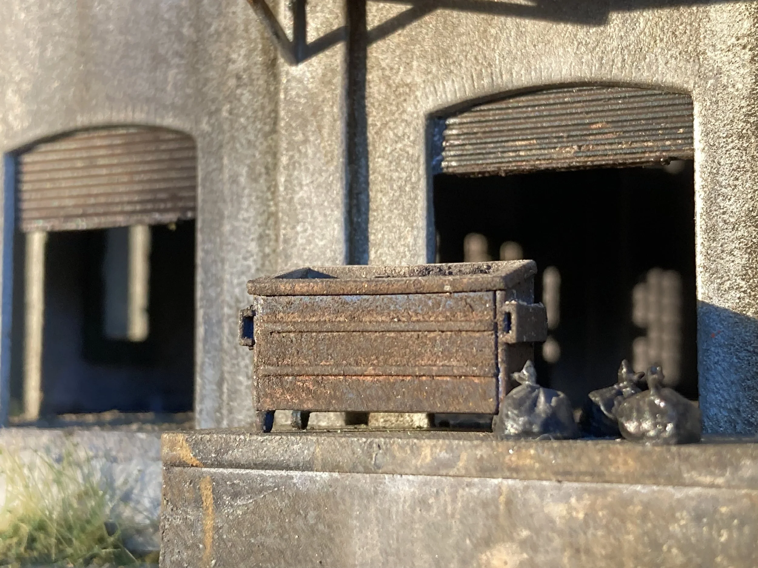 Close-up of a rusted metal structure with rectangular openings and chains hanging from the top, possibly part of an industrial or architectural feature.
