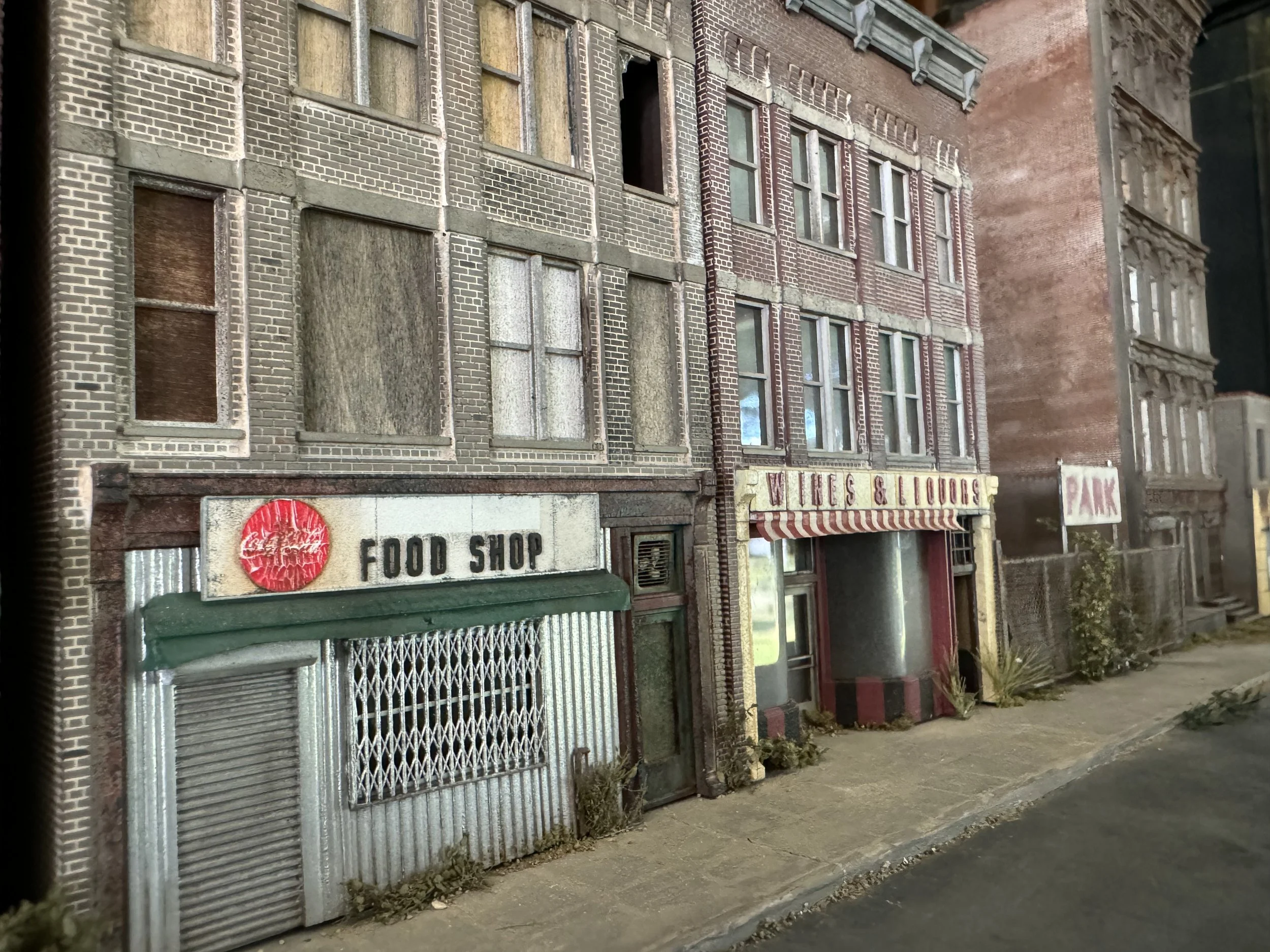 Old brick building with boarded-up windows and metal security gates in an urban setting.