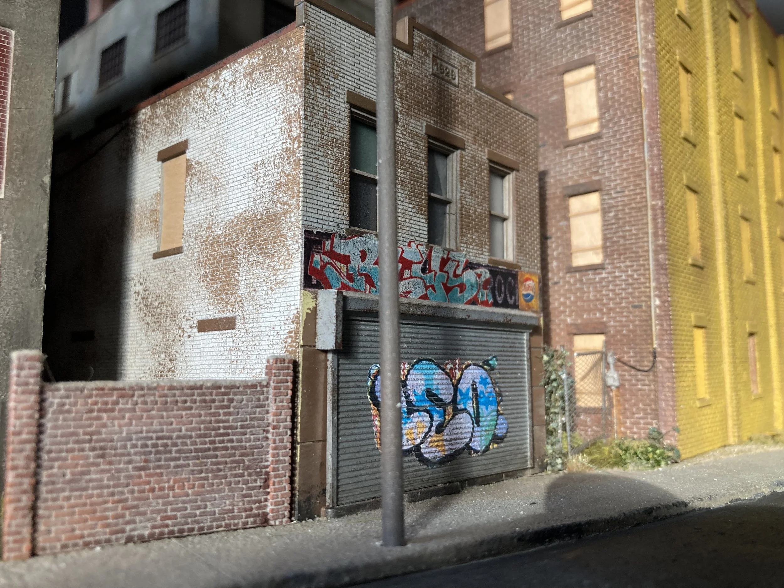 A model of a city building wall with graffiti on the lower part, brick textures, and a street scene.