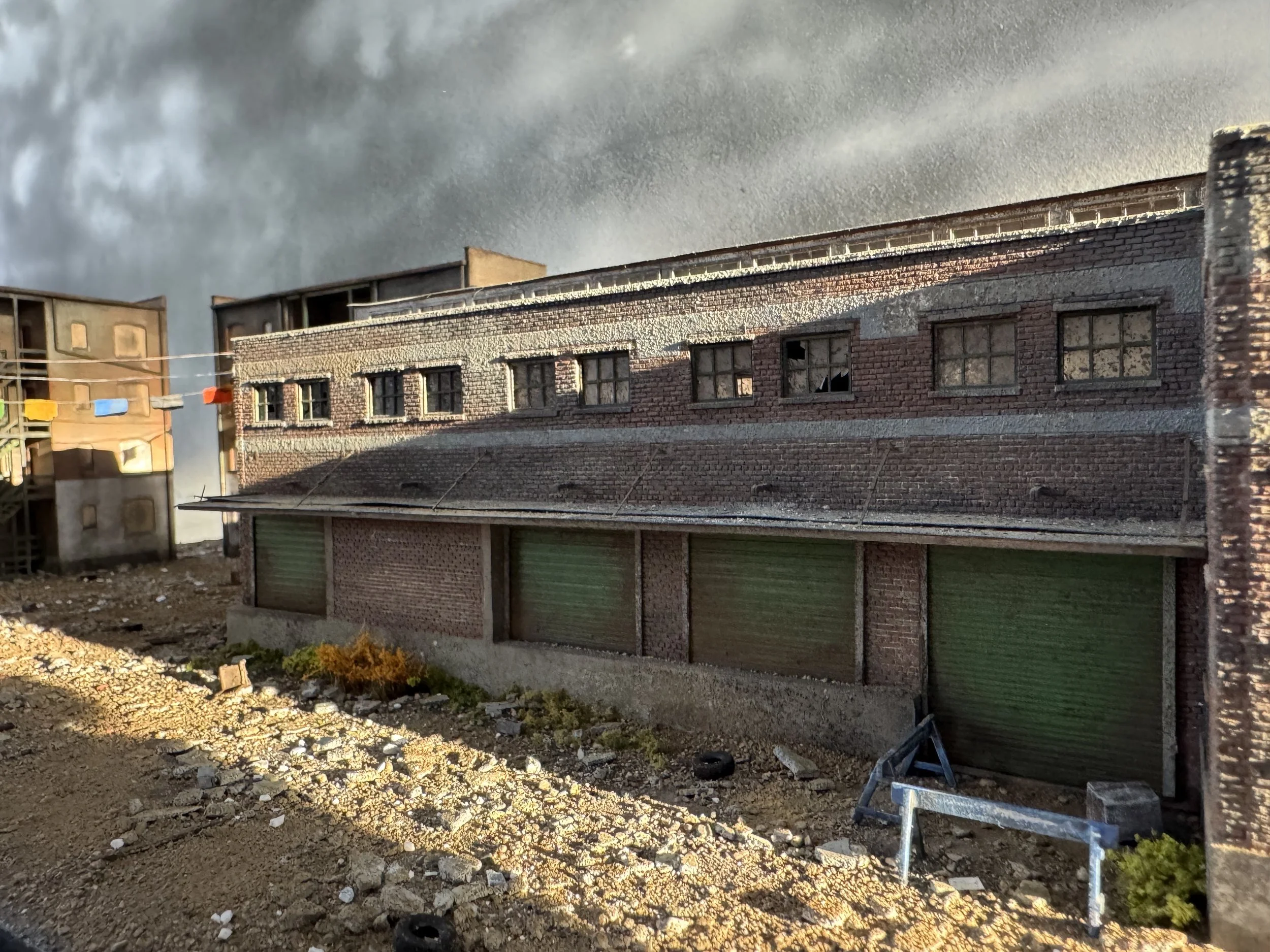 Urban street with brick building, some windows broken, and dark stormy clouds in the sky.