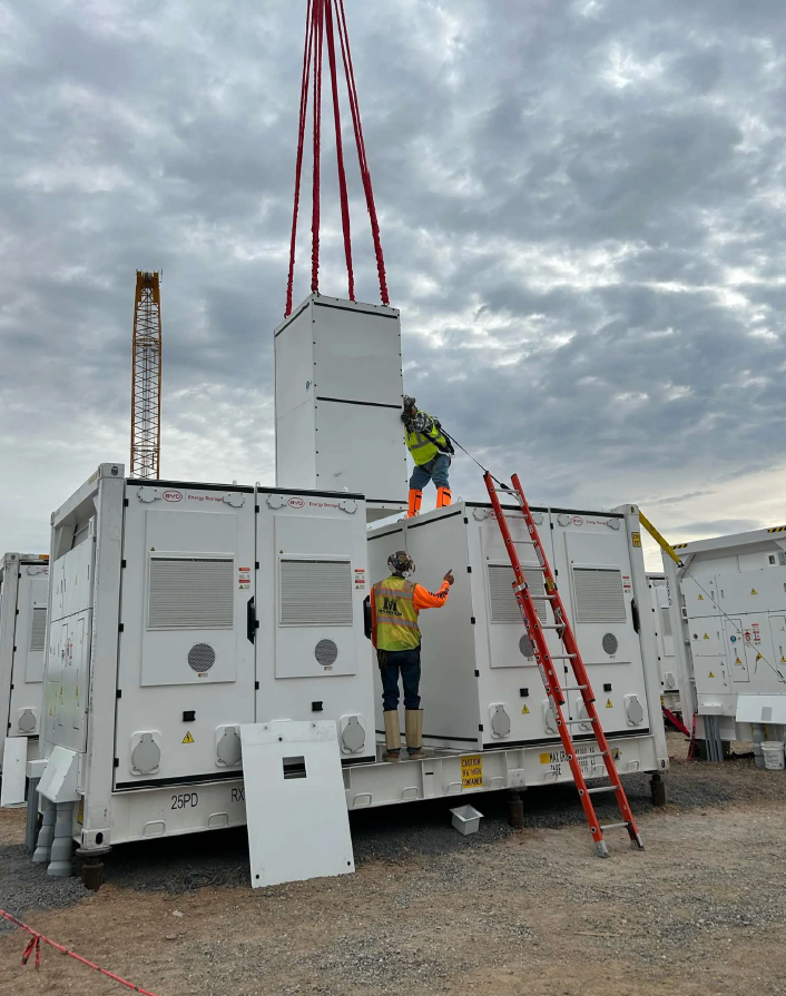 Two workers place a battery energy container on a deck