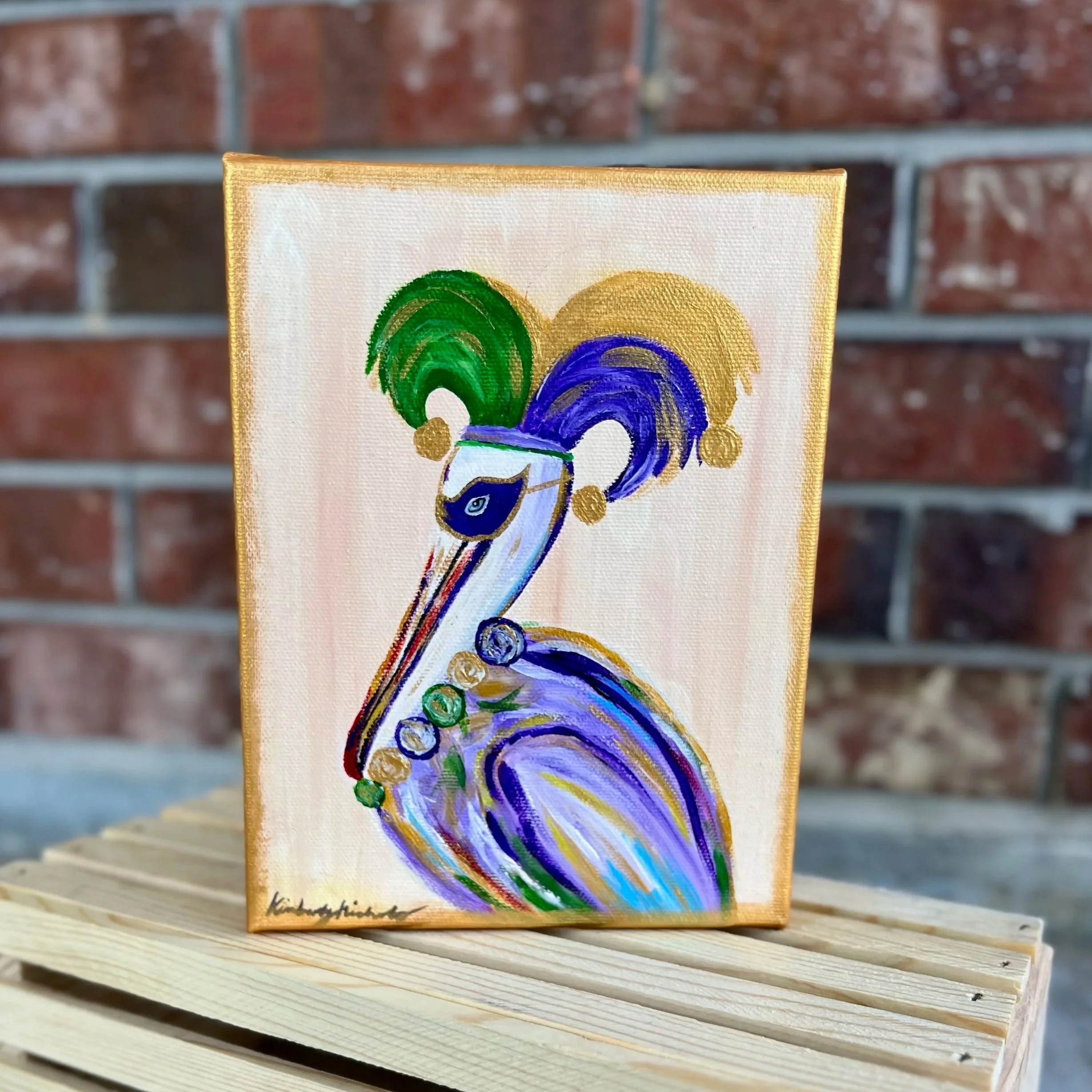 Painting of a colorful pelican with green, blue, and gold feathers on a cream background, with the artist's signature at the bottom.