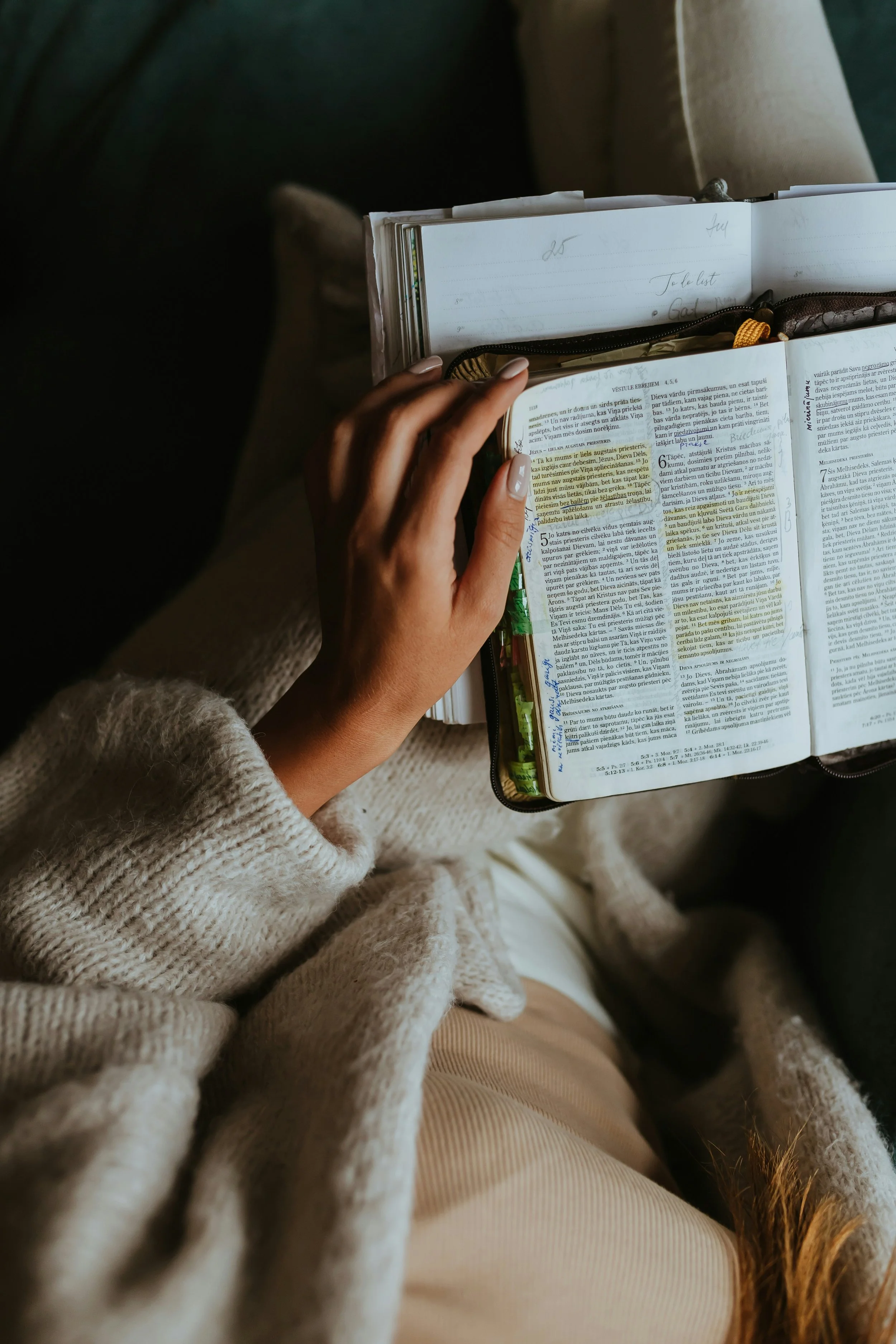 A women sitting and reading a bible and journaling.