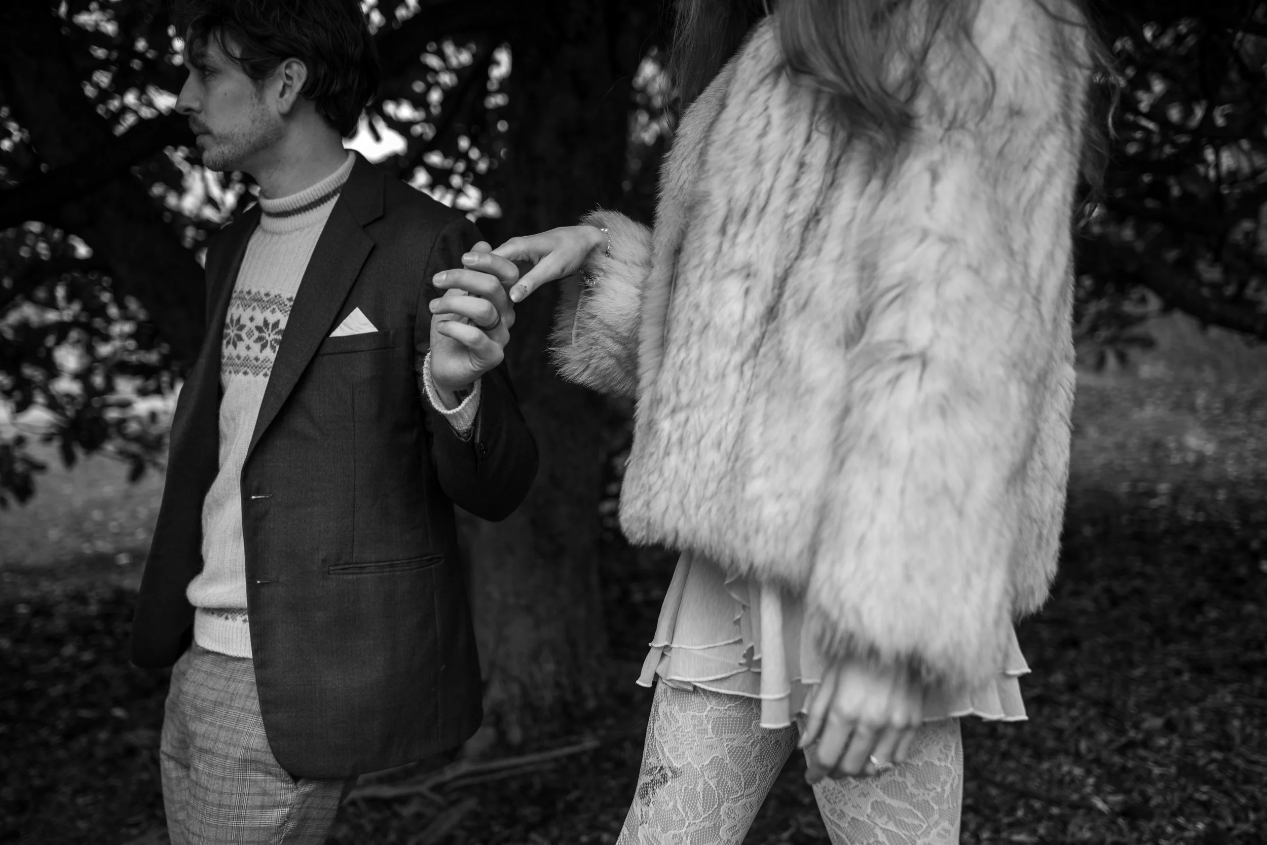 A man and woman holding hands while walking outdoors, with focus on their hands and bodies, showing a close-up of their clasped hands.