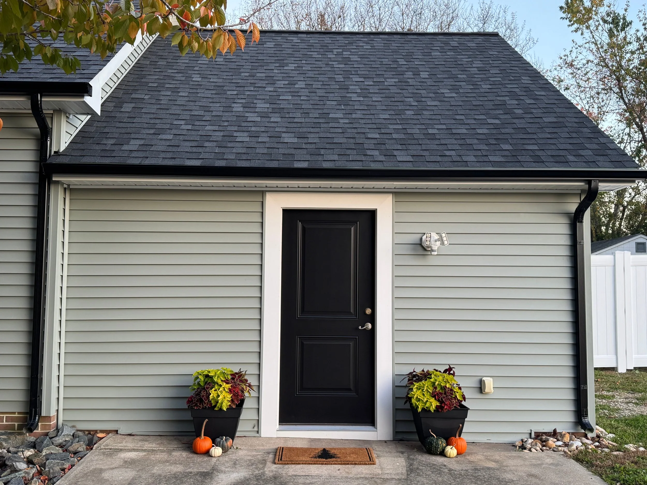 House with horizontal vinyl siding, a new black front door with decorative trim, and a small porch area.