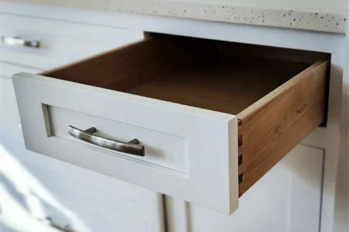 Open kitchen drawer with white front panel and wooden interior.