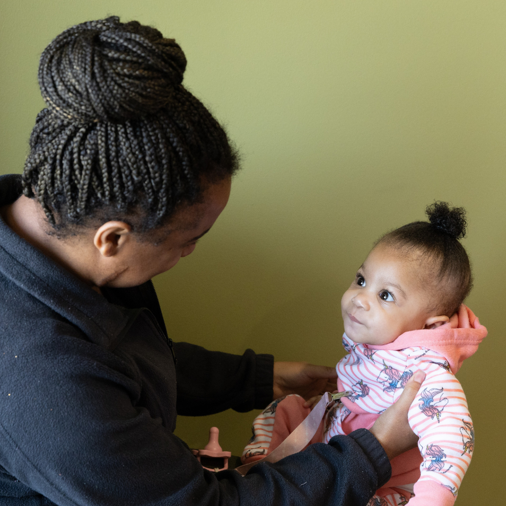 A Black baby smiling at a caregiver