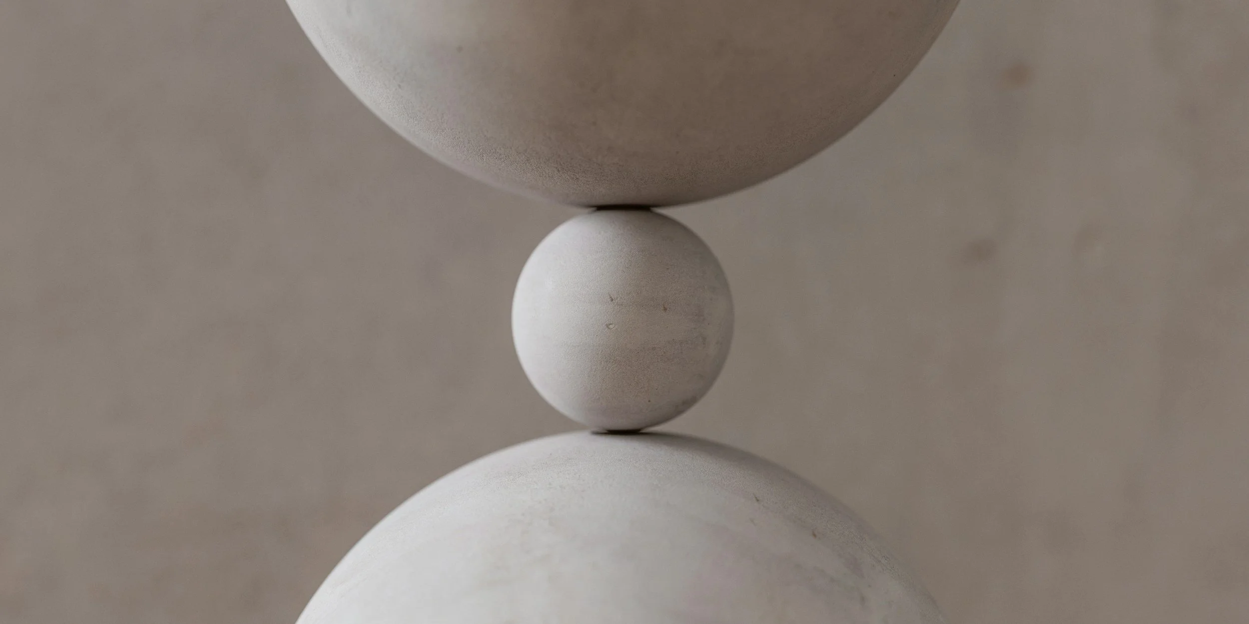 Stacked smooth beige ceramic spheres aligned vertically.