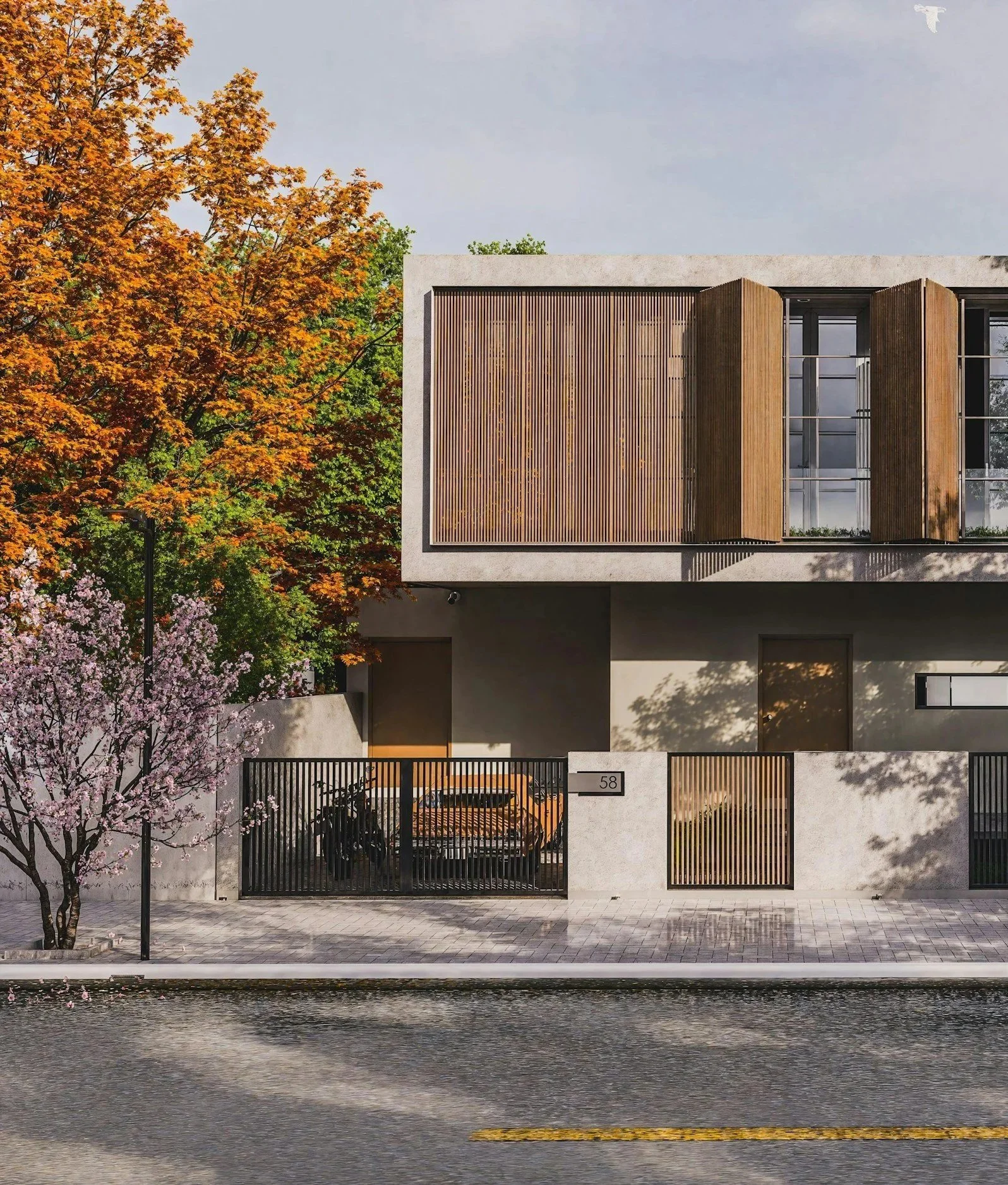 Modern residential building with concrete and wooden facade, large windows with shutters, black gate, and pink flowering trees, water body in the foreground.