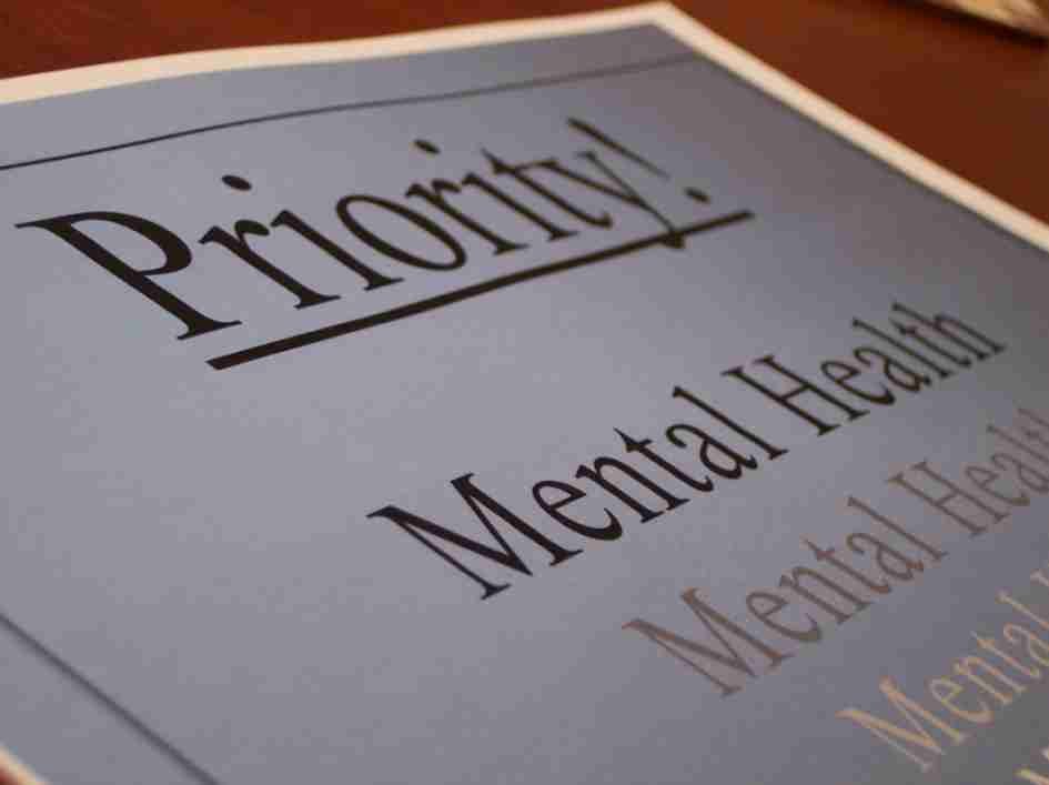 A white piece of paper is shown at an angle, with the words mental health visible in black ink.
