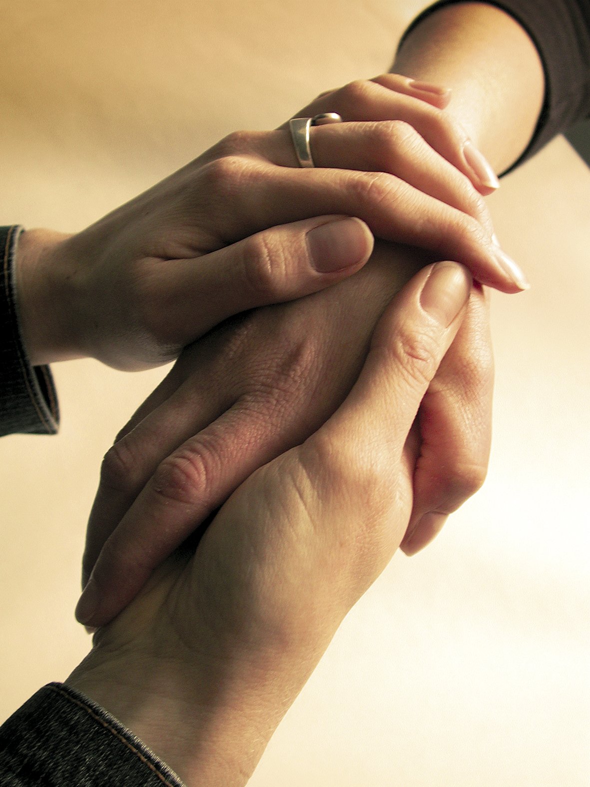 Two white hands clasped in a kind gesture.