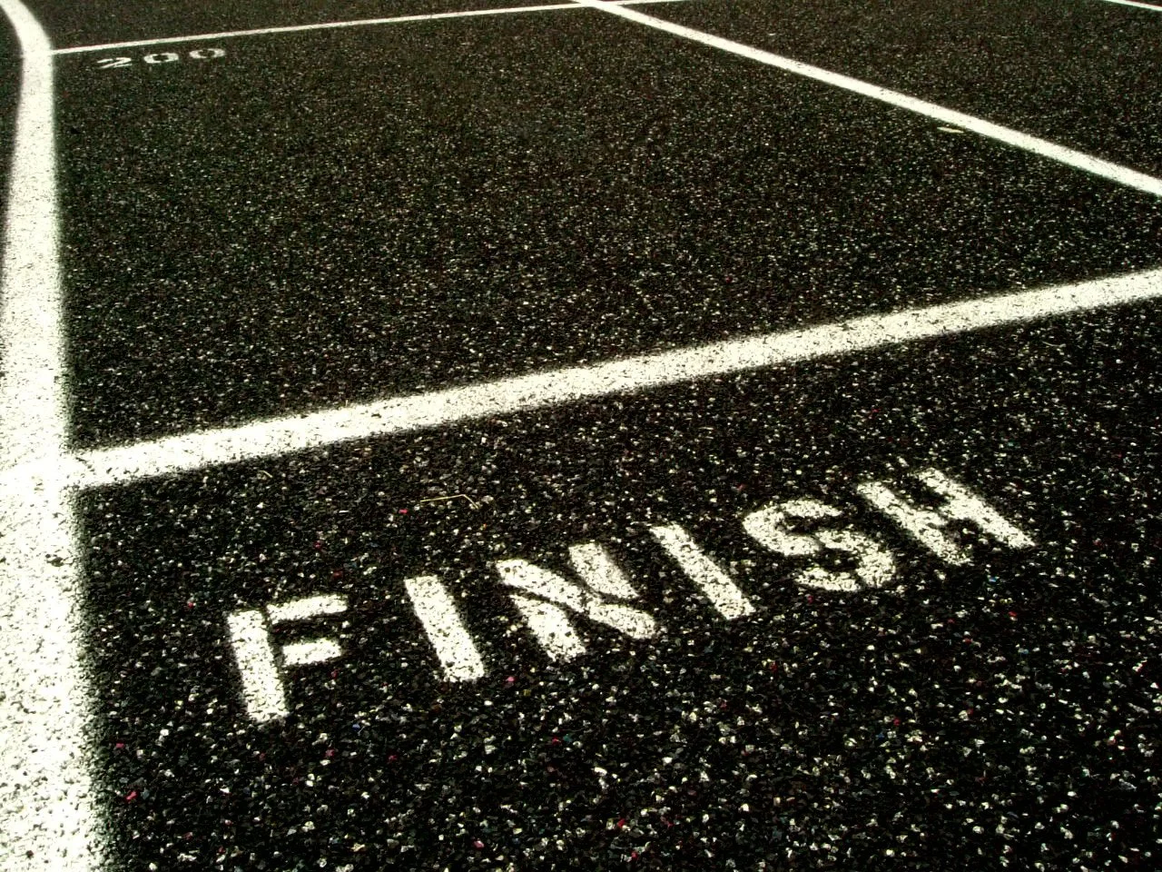 A close up of the word finish and a white line above it on black asphalt.