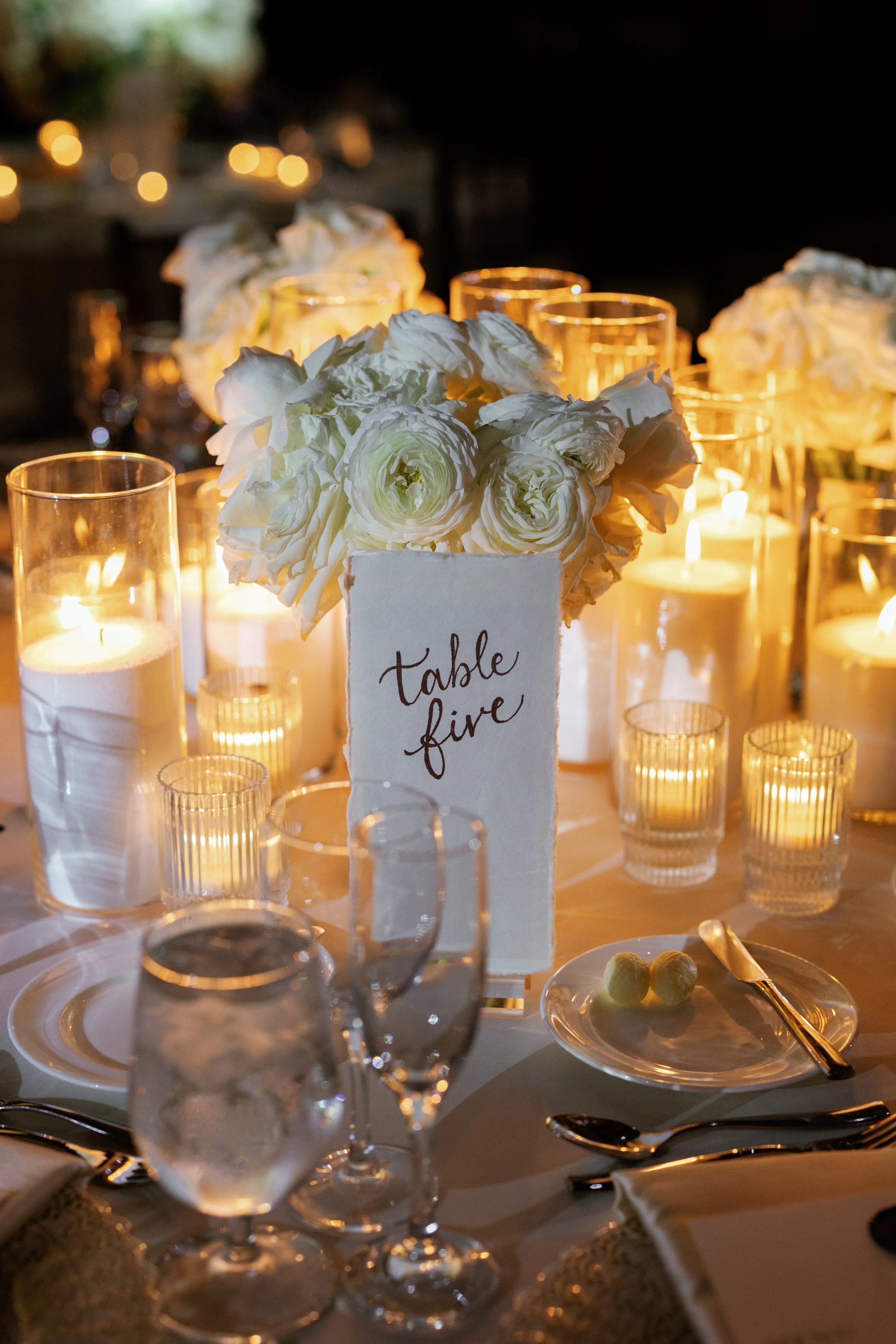 Elegant dining table with floral centerpiece, candles, and place setting, indicating a formal event or celebration.