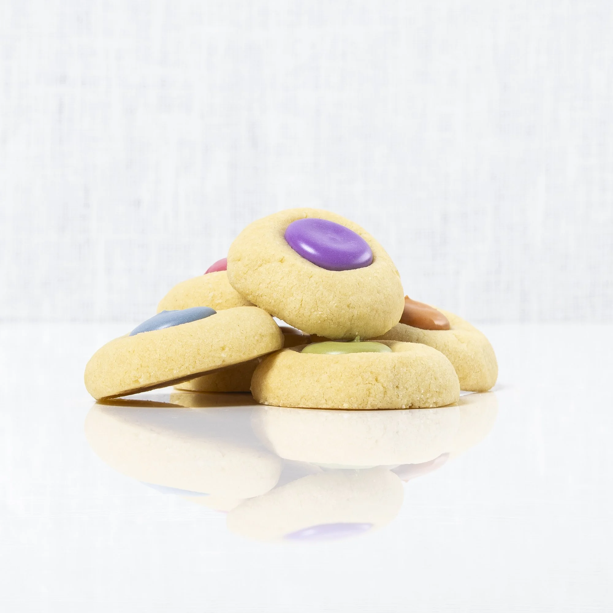 Thumbprint Cookies -

These little “two-bite delights” are shortbread-style butter cookies with a vanilla icing center. They can be color-customized to fit any theme or occasion. Simple but delicious, they are the perfect addition to any dessert spre